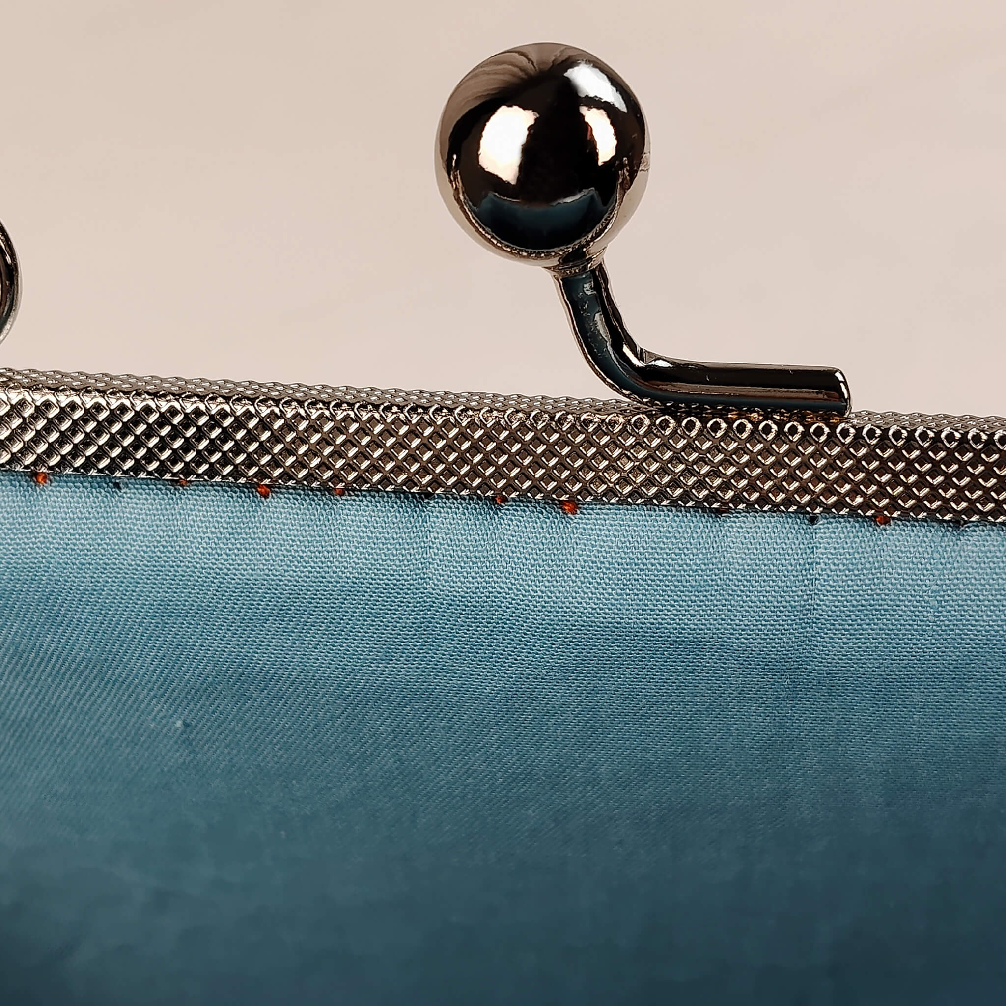 Close-up detail of Acever A001 clutch bag showing ornate engraved silver kiss-lock frame with twin ball clasp and teal polyester fabric texture