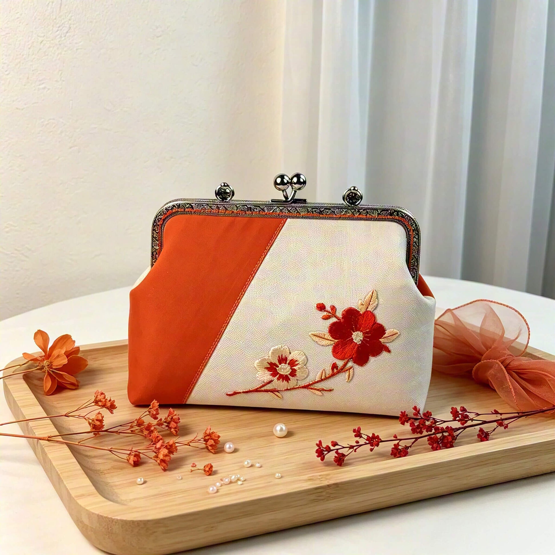 Acever A001 plum blossom clutch bag lifestyle shot showing ivory and orange two-tone body with red embroidered plum blossom branch and silver kiss-lock frame