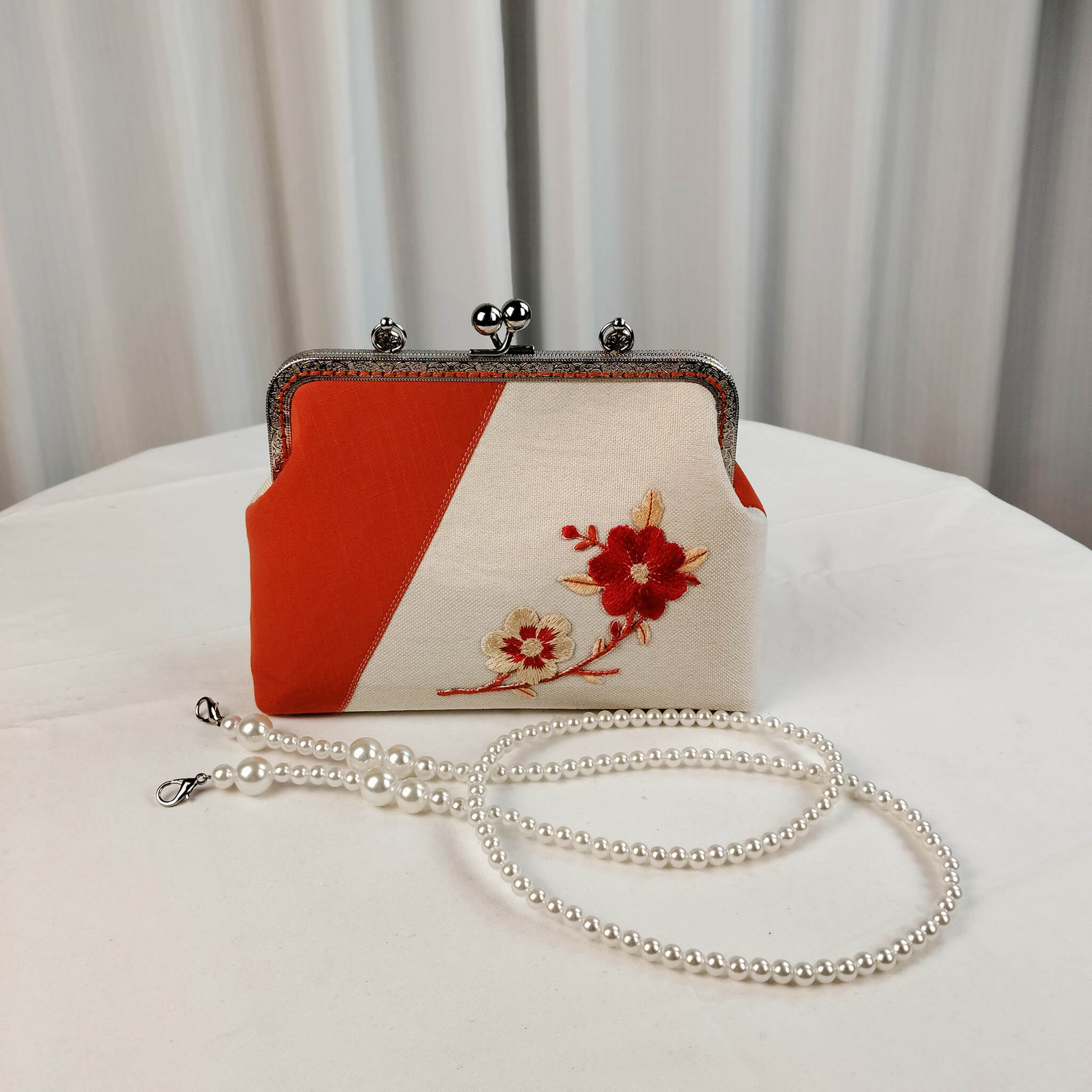 Acever A001 plum blossom clutch bag lifestyle shot showing bag styled with autumn leaves and flowers highlighting the ornate silver frame and embroidered motif