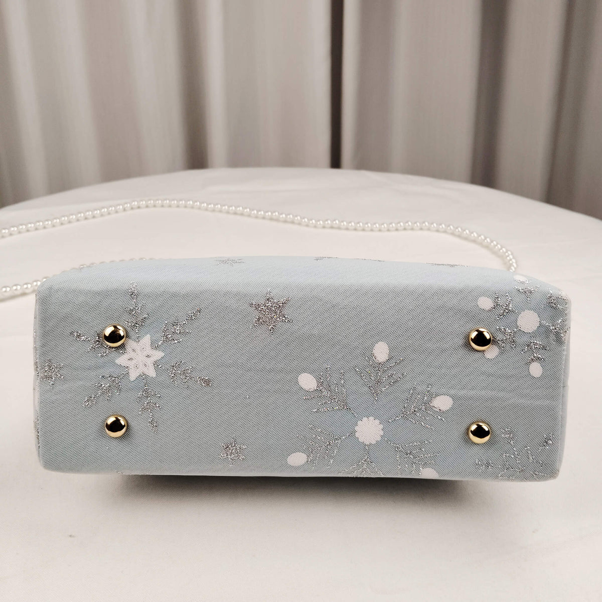 Bottom view of Acever A002 snowflake and star clutch bag showing powder blue polyester base with star pattern detail
