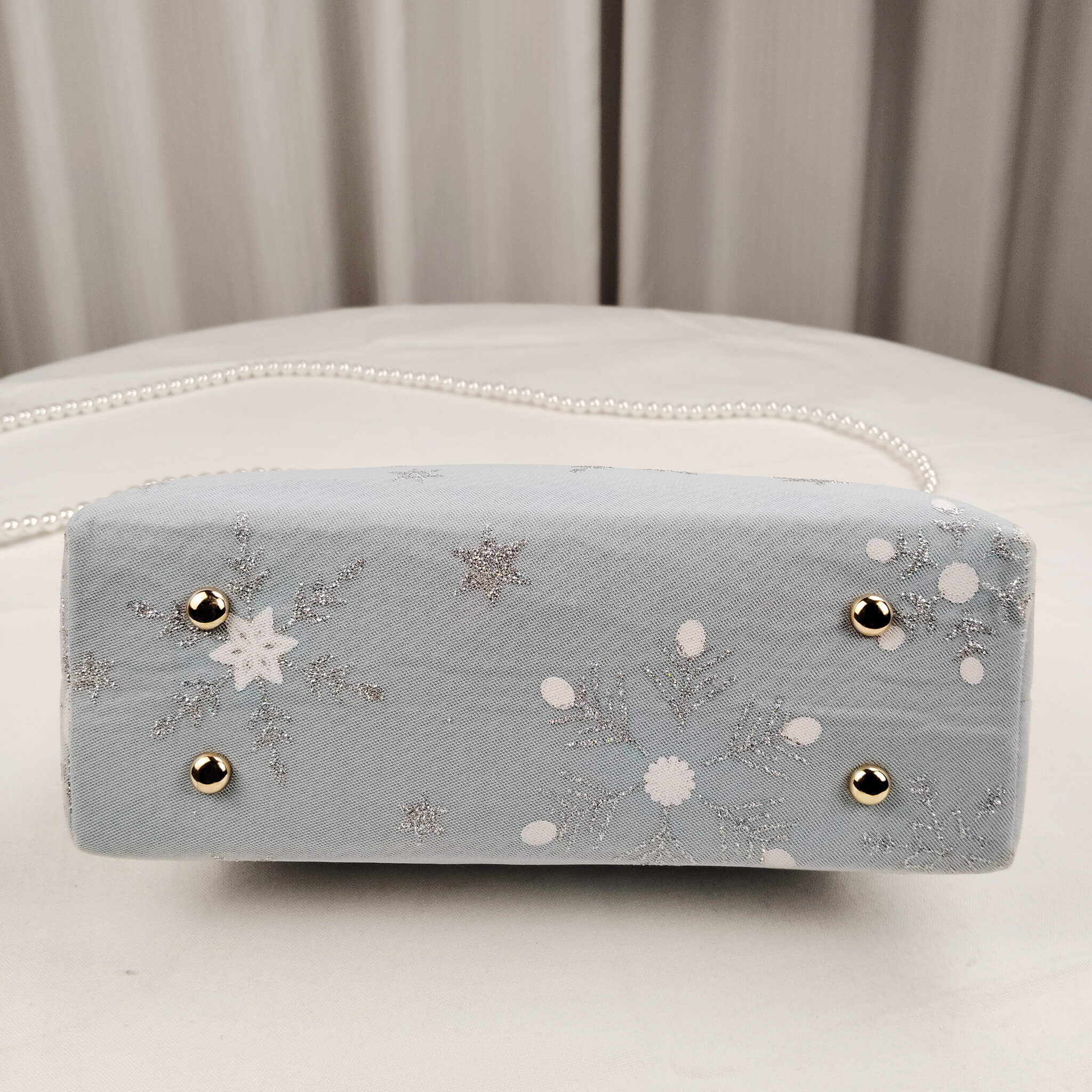 Bottom view of Acever A002 snowflake and star clutch bag showing powder blue polyester base with star pattern detail