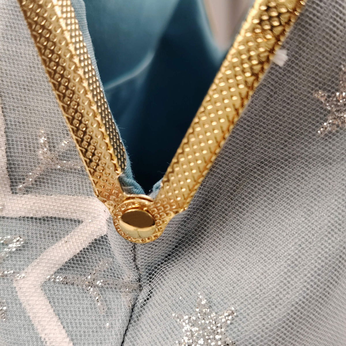 Close-up detail of Acever A002 clutch bag showing silver glitter snowflake embroidery and white star motif on powder blue polyester fabric