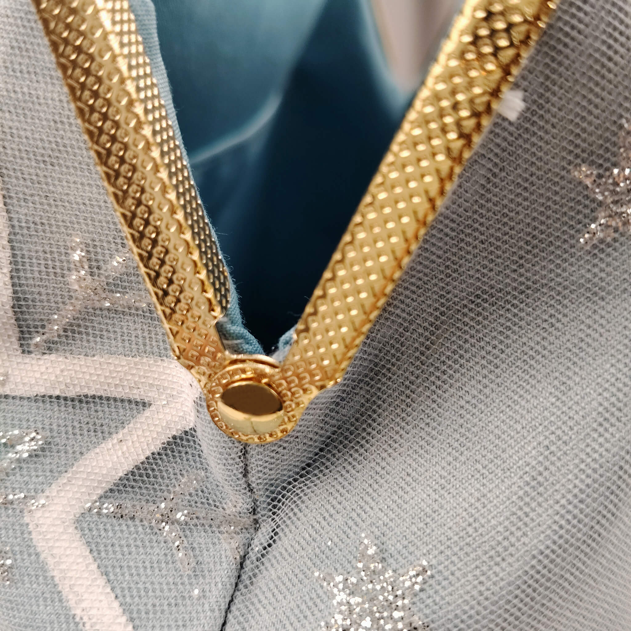 Close-up detail of Acever A002 clutch bag showing silver glitter snowflake embroidery and white star motif on powder blue polyester fabric