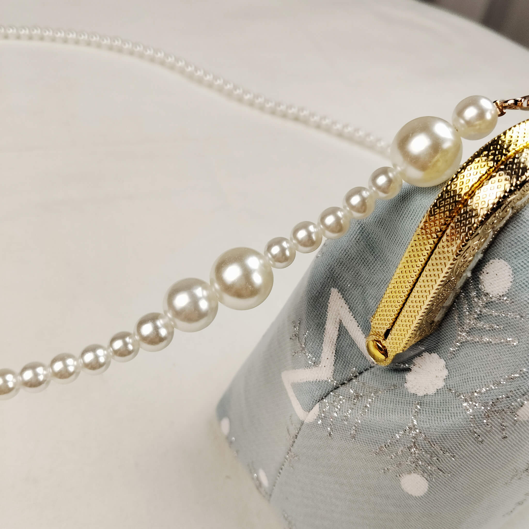 Close-up detail of Acever A002 clutch bag showing gold ornate filigree kiss-lock frame with twin ball clasp and pearl bead strap attachment