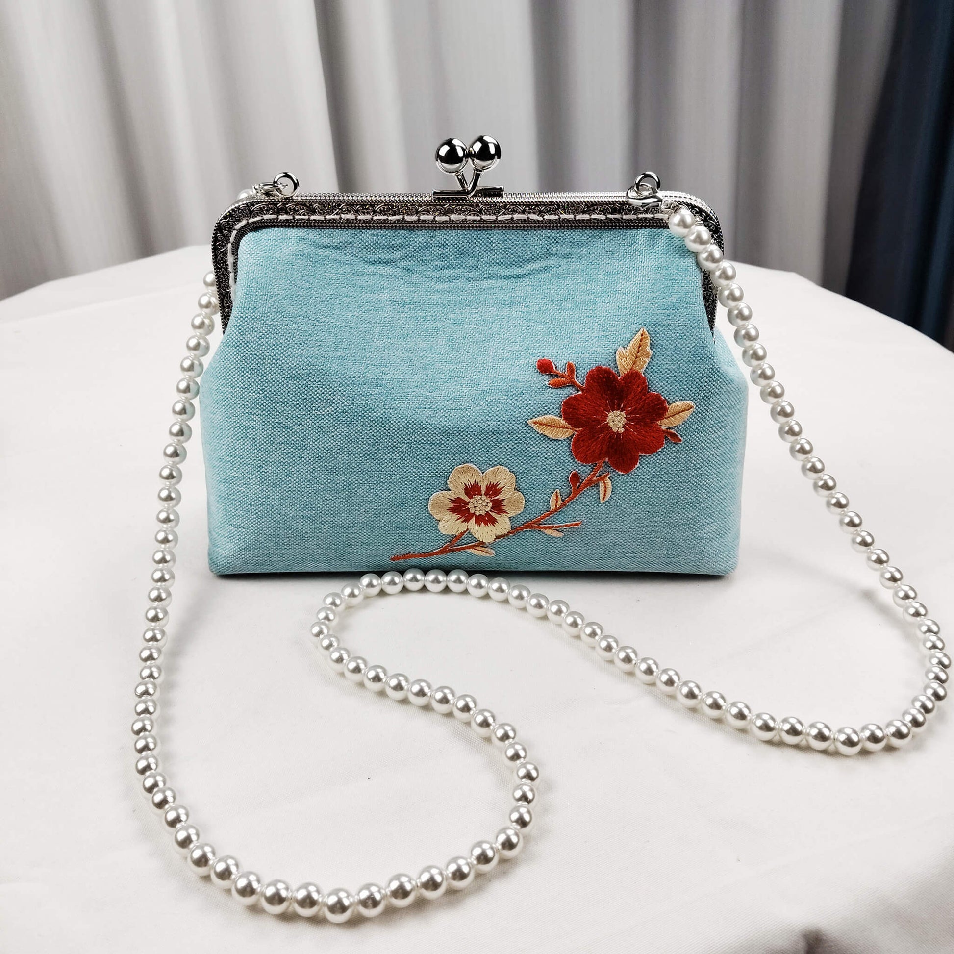 Acever A003 cherry blossom clutch bag lifestyle shot on white background showing front view with silver ornate kiss-lock frame twin ball clasp and pearl bead strap