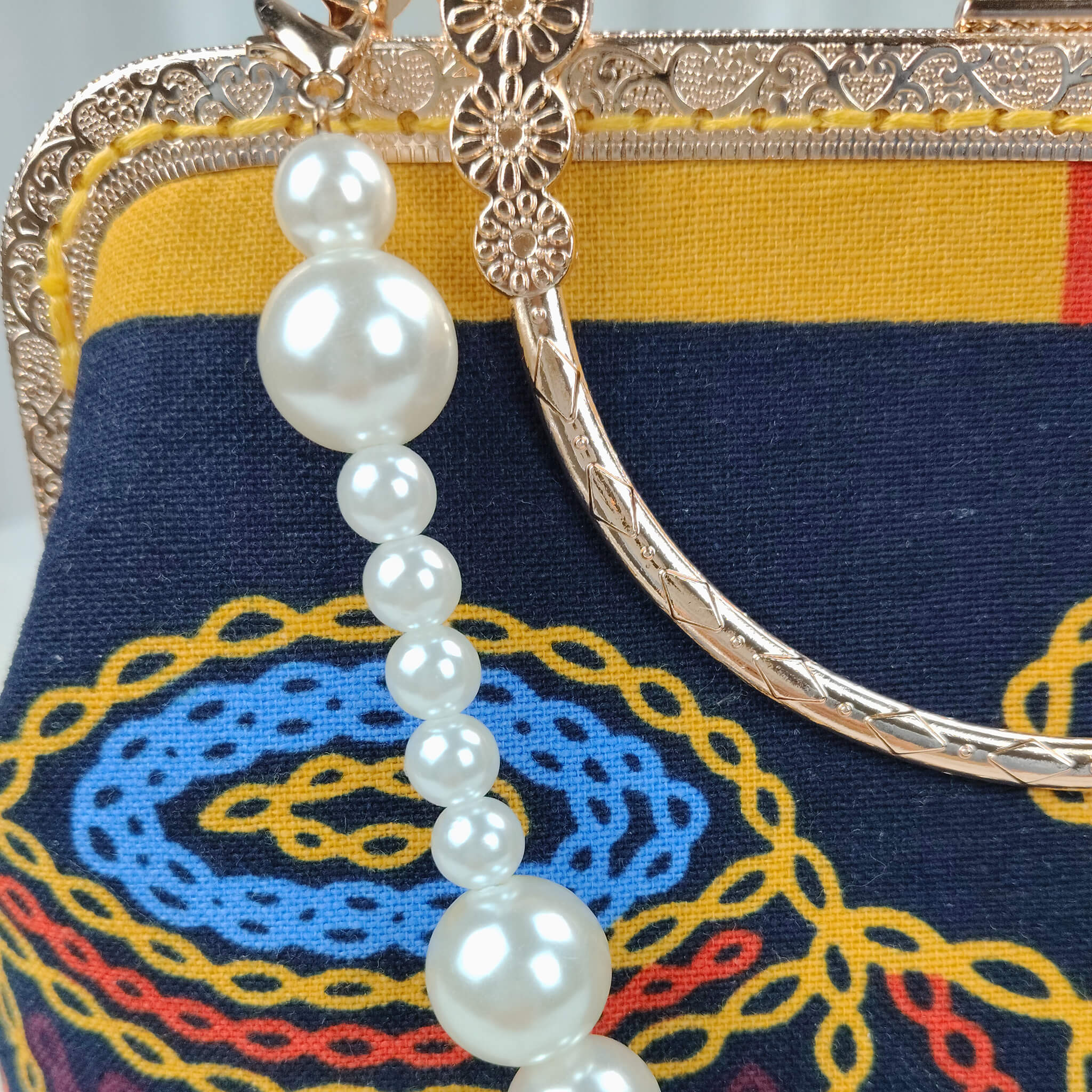 Close-up detail of Acever A004 clutch bag showing gold ornate filigree kiss-lock frame with twin ball clasp side ring loops and amber crystal accents