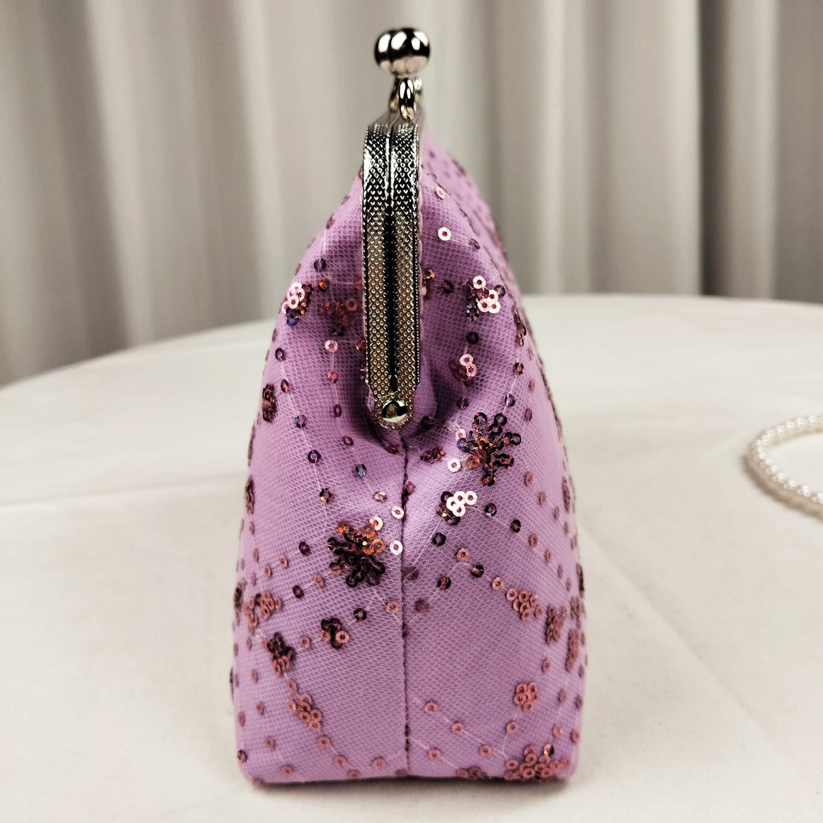 Side view of Acever A005 sequin floral quilted clutch bag showing lavender polyester gusset with rose gold sequin flower clusters diamond quilting and gunmetal frame edge