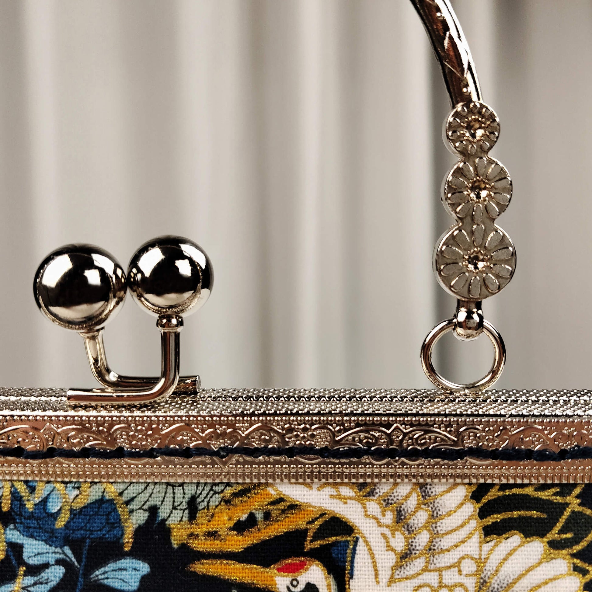 Close-up detail of Acever A006 bag showing silver ornate filigree kiss-lock frame with twin ball clasp and decorative silver top handle with floral bead accents