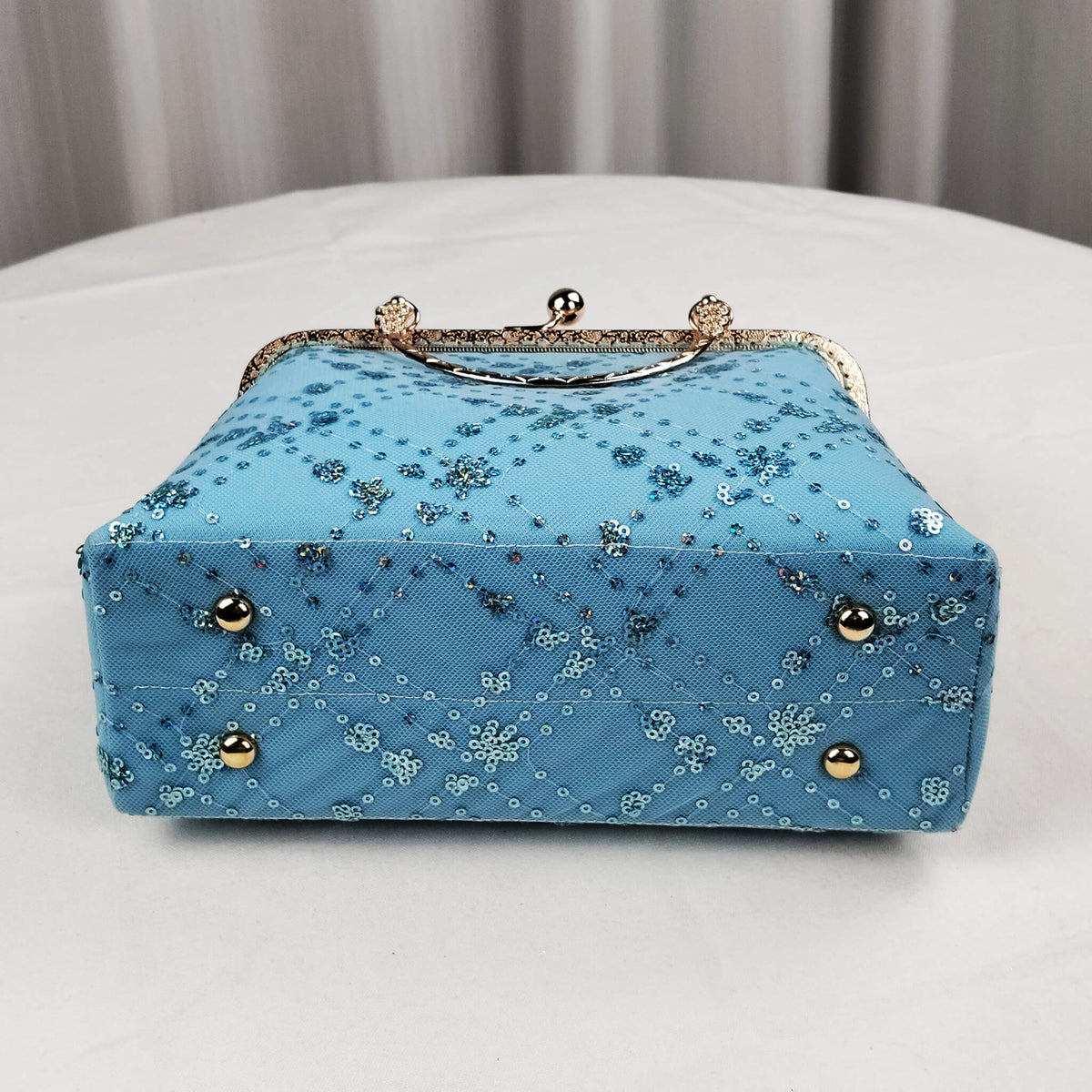 Bottom view of Acever A007 blue sequin floral quilted clutch bag showing sky blue polyester base with sheer tulle overlay and scattered iridescent sequin dot accents