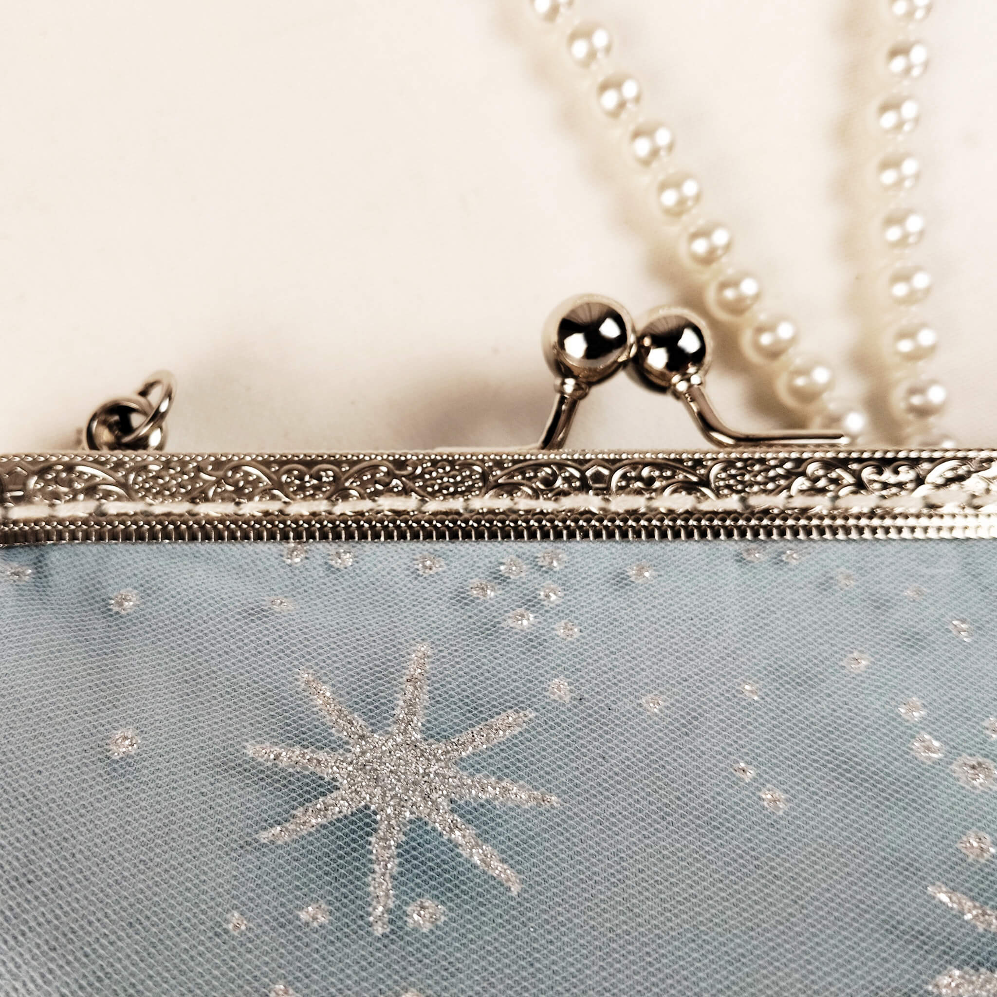 Close-up detail of Acever B001 clutch bag showing silver ornate filigree kiss-lock frame with twin ball clasp and silver lobster clasp large pearl bead strap connector