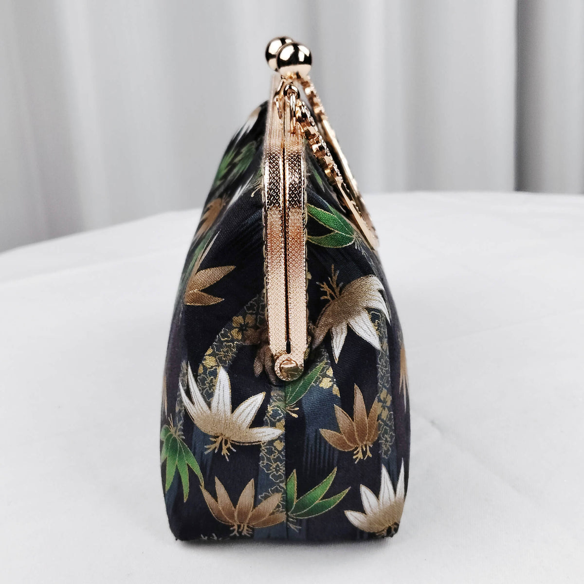 Side view of Acever B002 lotus and leaf jacquard clutch bag showing midnight navy jacquard gusset with lotus and leaf print rose gold textured zipper side detail and rose gold chain strap