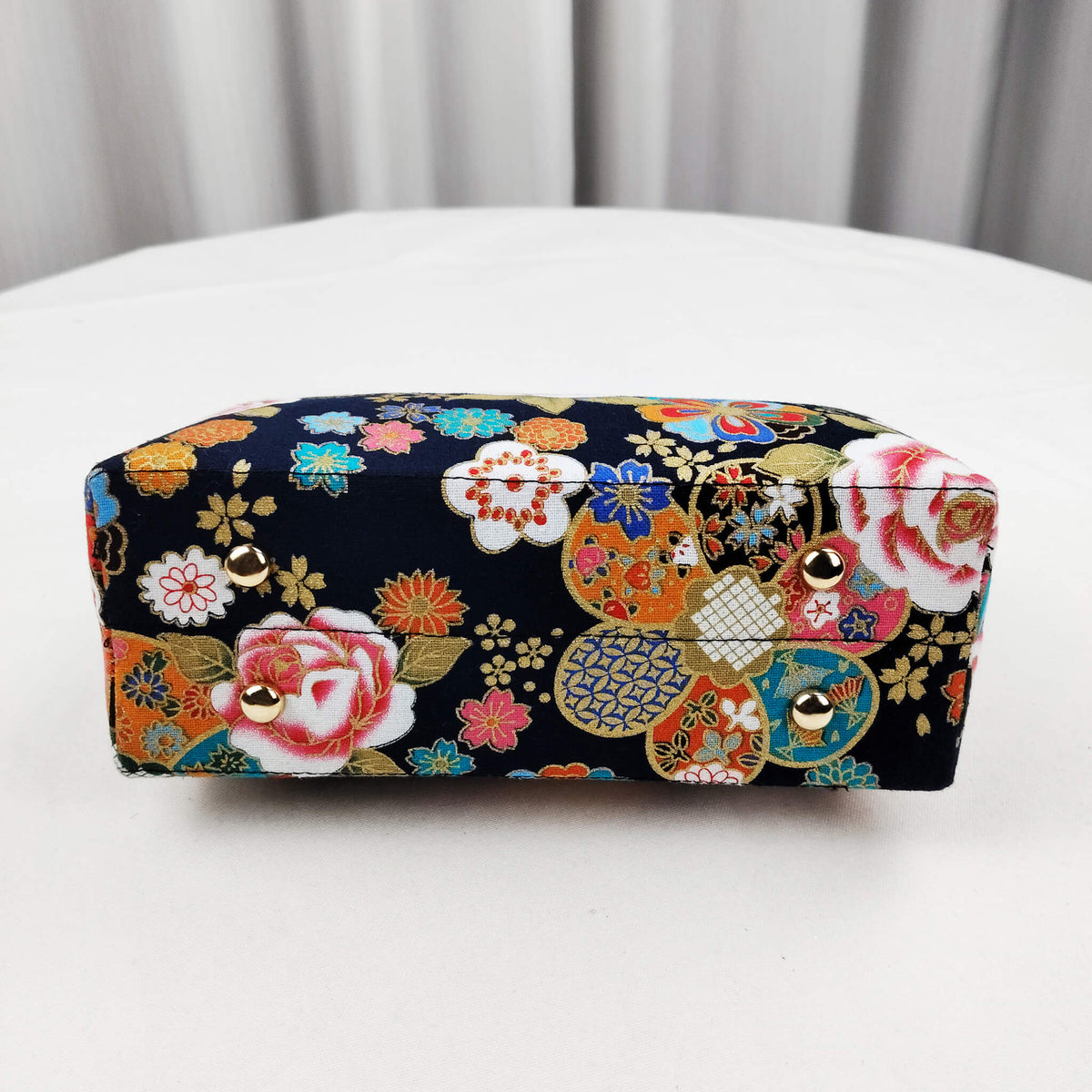 Bottom view of Acever B004 Japanese Kinsai floral top handle bag showing midnight navy brocade base with all-over white pink peony teal orange blossom and golden chrysanthemum print with metallic gold thread highlights
