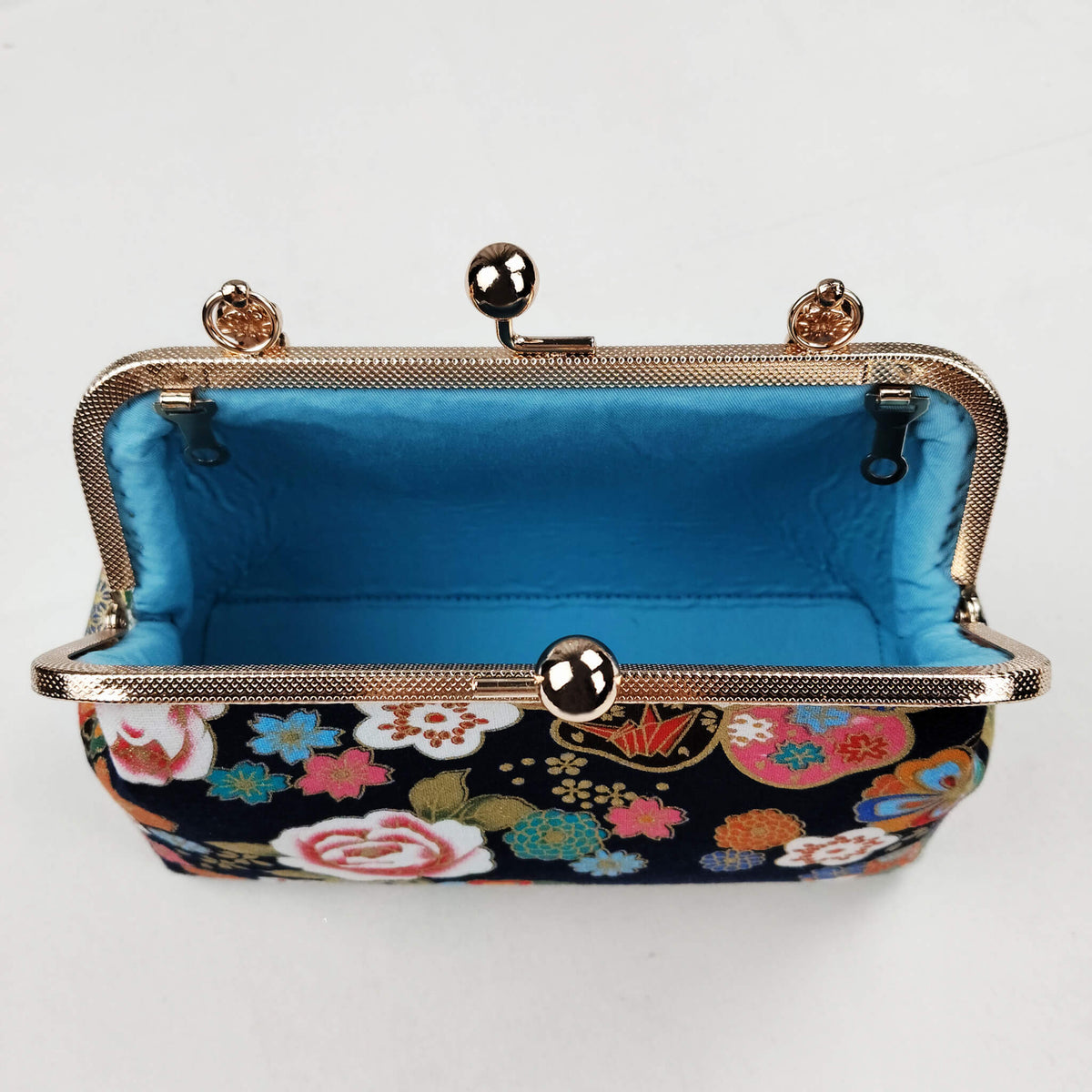 Interior view of Acever B004 Japanese Kinsai floral bag open showing bright turquoise sky blue smooth satin lining with single open compartment small interior zip pocket and antique gold frame edge with amber crystal clasp accents
