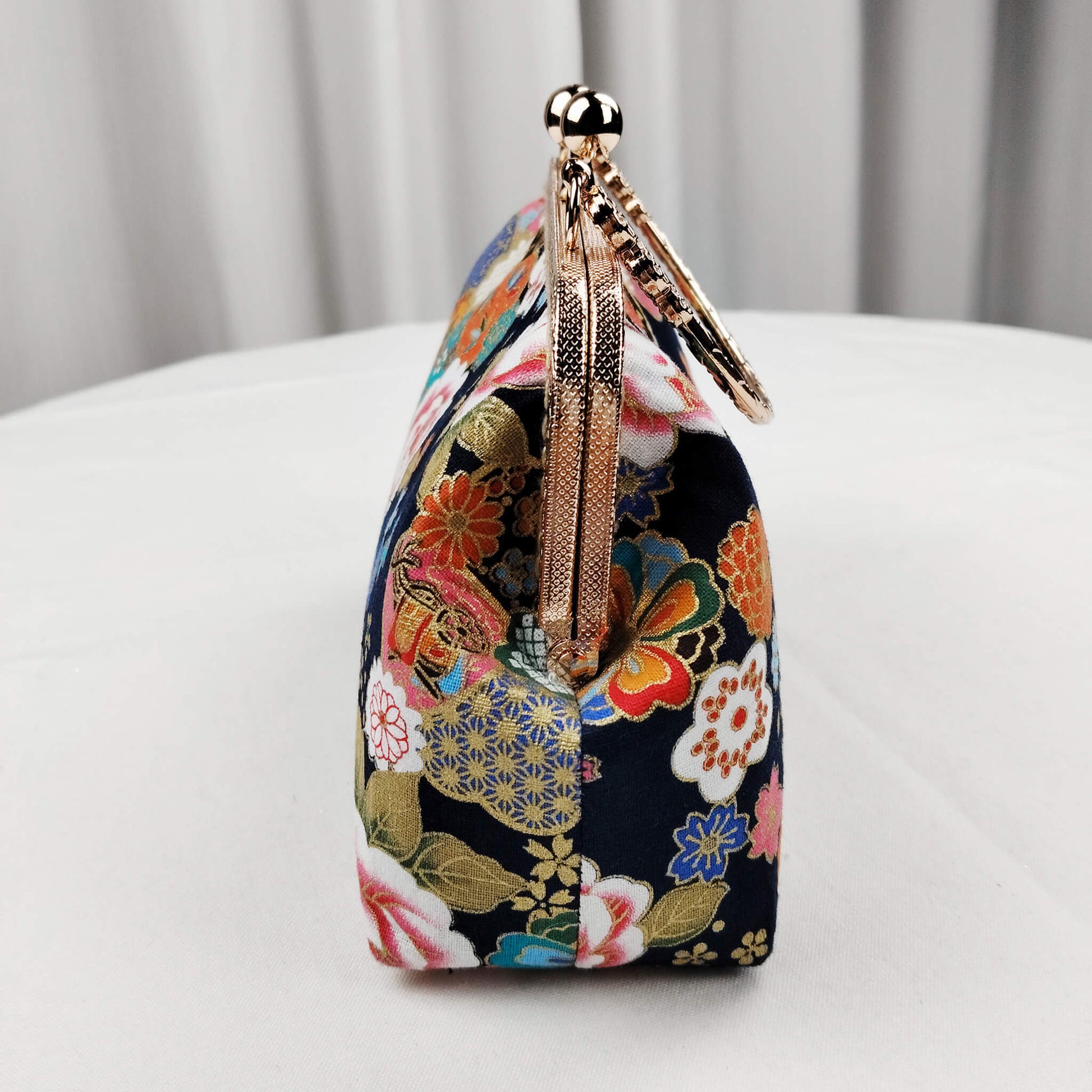 Side view of Acever B004 Japanese Kinsai floral top handle bag showing midnight navy brocade gusset with white pink peony and teal blossom print gold textured zipper side detail and antique gold rope chain strap