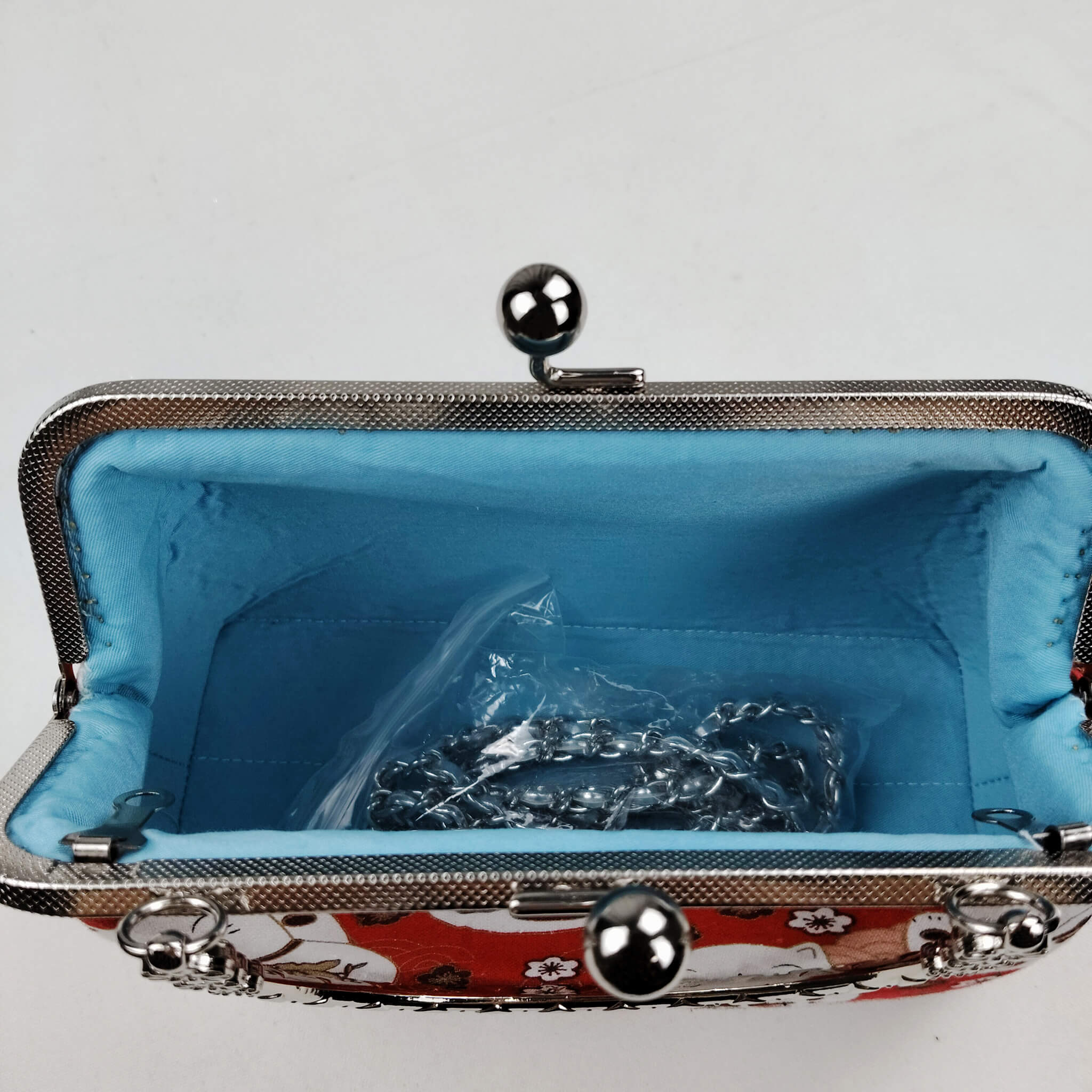 Interior view of Acever B006 Lucky Cat Maneki-Neko bag open showing sky blue smooth satin lining with single open compartment and gunmetal double twin ball clasp frame edge with flat-link chain strap stored inside