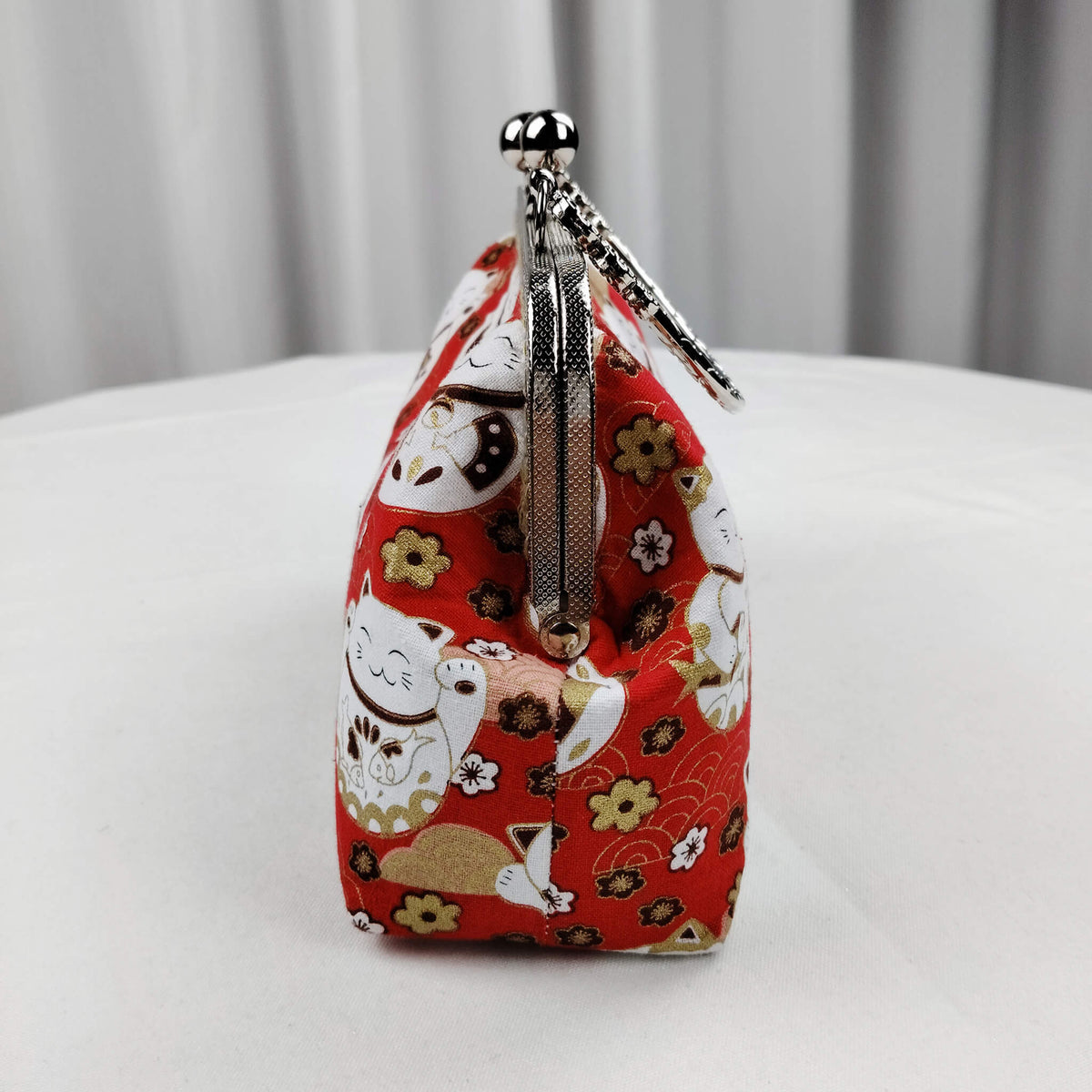Left side view of Acever B006 Lucky Cat Maneki-Neko top handle bag showing vivid red polyester gusset with white lucky cats and plum blossom print gunmetal textured zipper side detail and gunmetal top handle with triple floral medallion connectors
