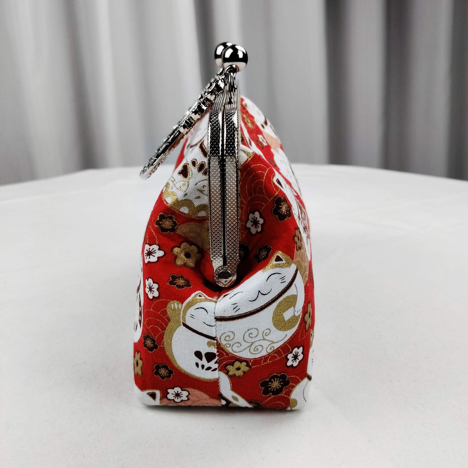 Right side view of Acever B006 Lucky Cat Maneki-Neko top handle bag showing vivid red polyester gusset with white lucky cats and plum blossom print gunmetal textured zipper side detail and gunmetal flat-link chain strap with lobster clasp