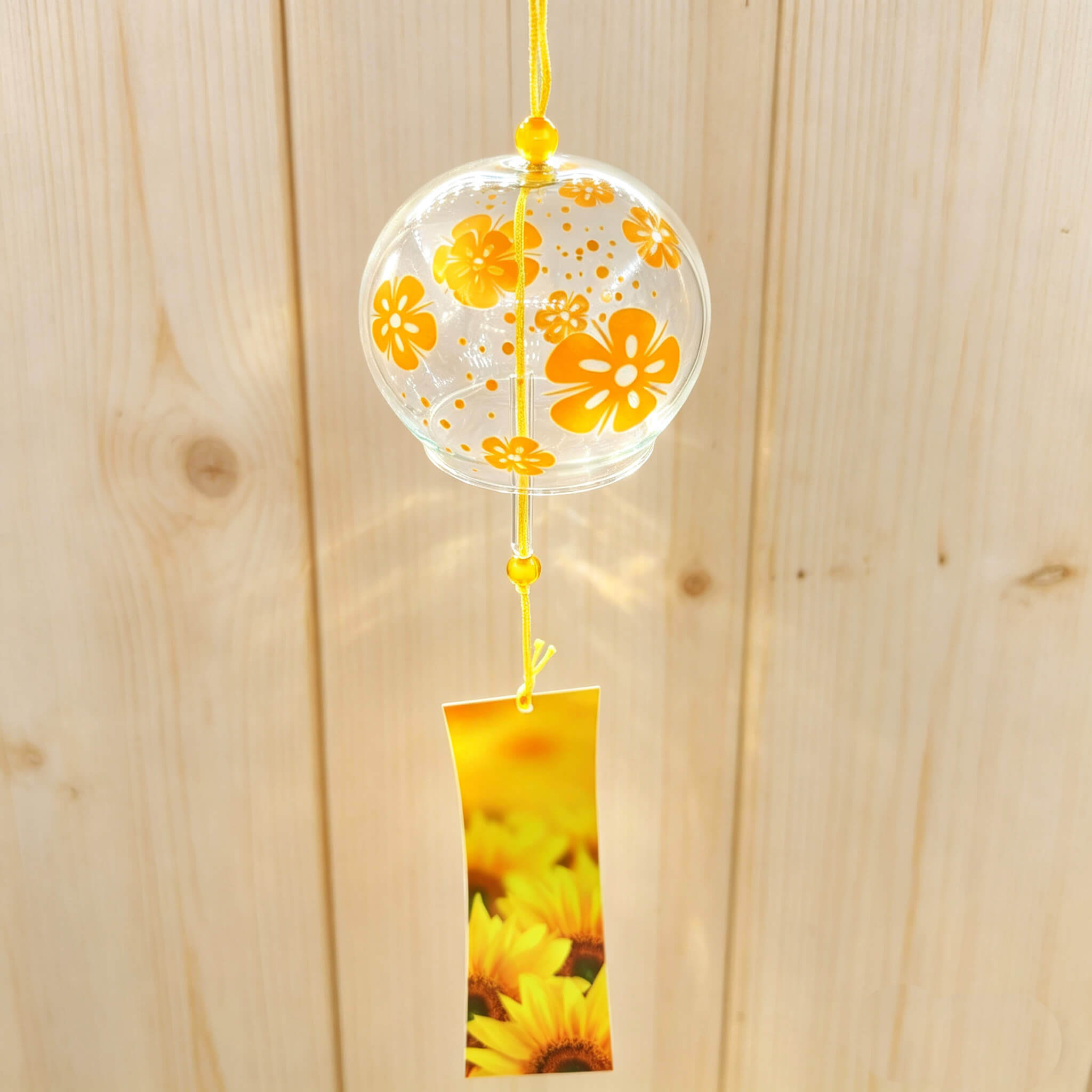 Acever golden flower glass wind chime X04 hanging against wooden wall showing full length with sunflower paper strip