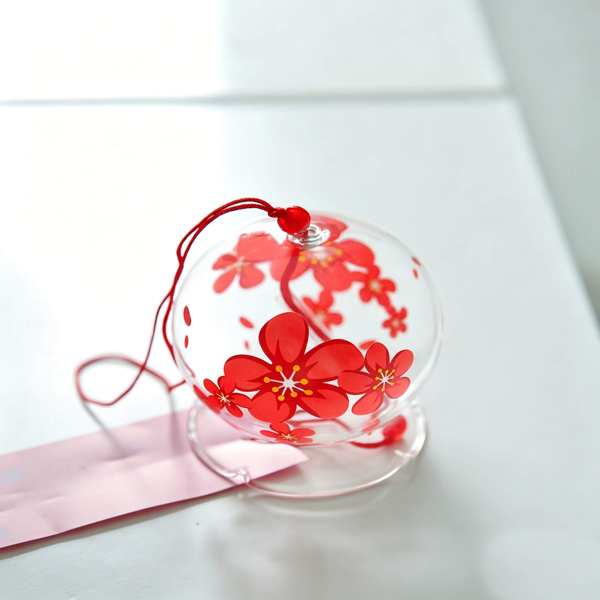 Close-up of Acever red sakura glass wind chime X06 showing waved scalloped edge clear globe with bold red cherry blossom pattern and red cord