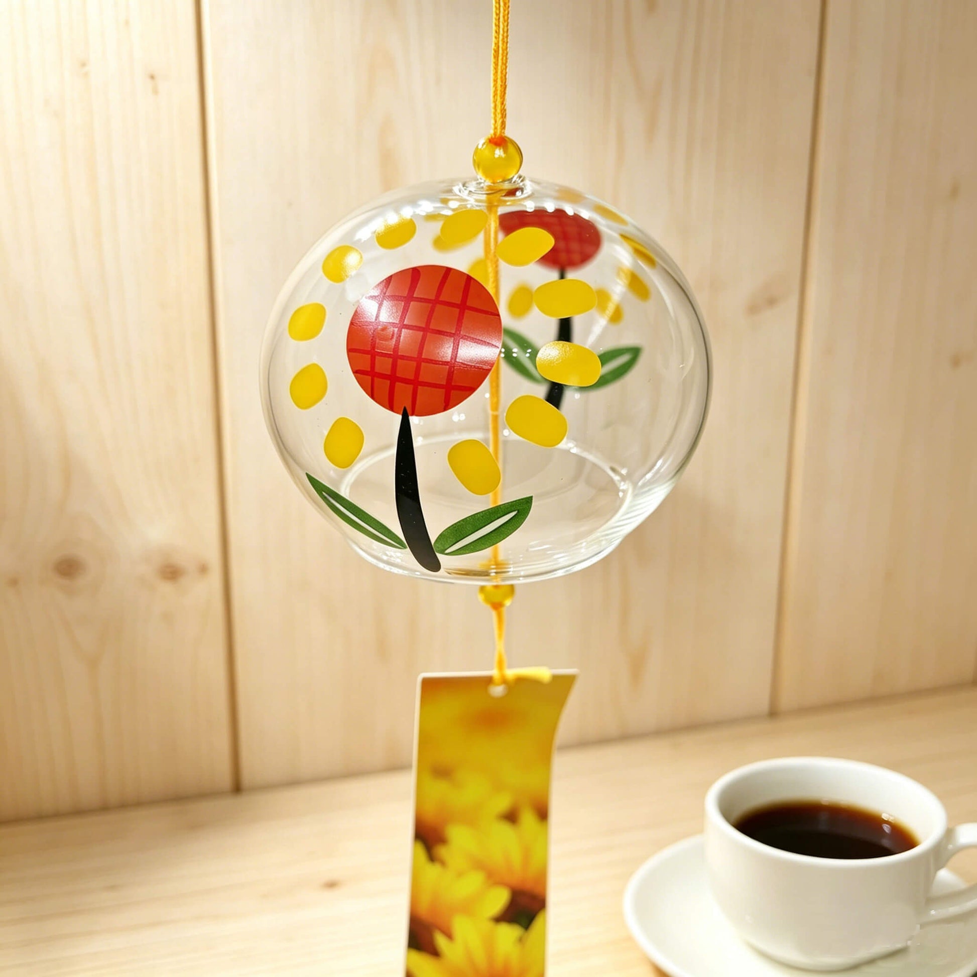 Close-up of Acever sunflower glass wind chime X13 showing bold sunflower with red crosshatch center and golden petals on clear flat-rim globe