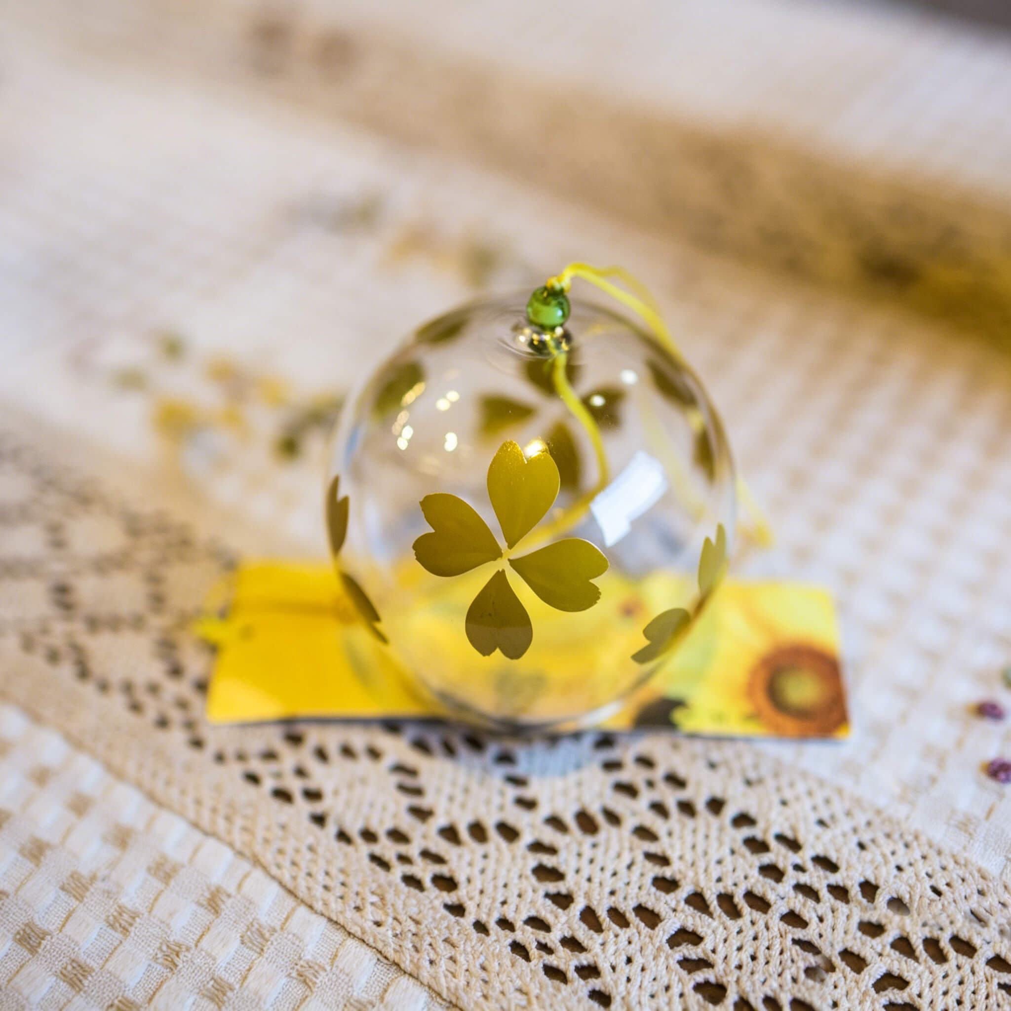 Close-up of Acever golden heart-petal flower glass wind chime X15 against black background showing clear globe with golden heart-shaped blossoms and amber bead