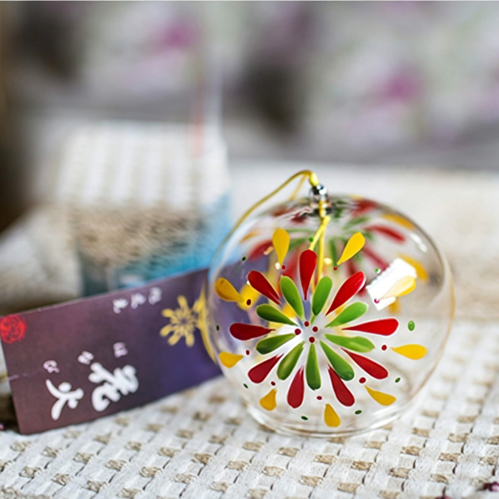 Acever fireworks hanabi glass wind chime X18 resting on table showing clear flat-rim globe with multicolour fireworks burst and  paper strip