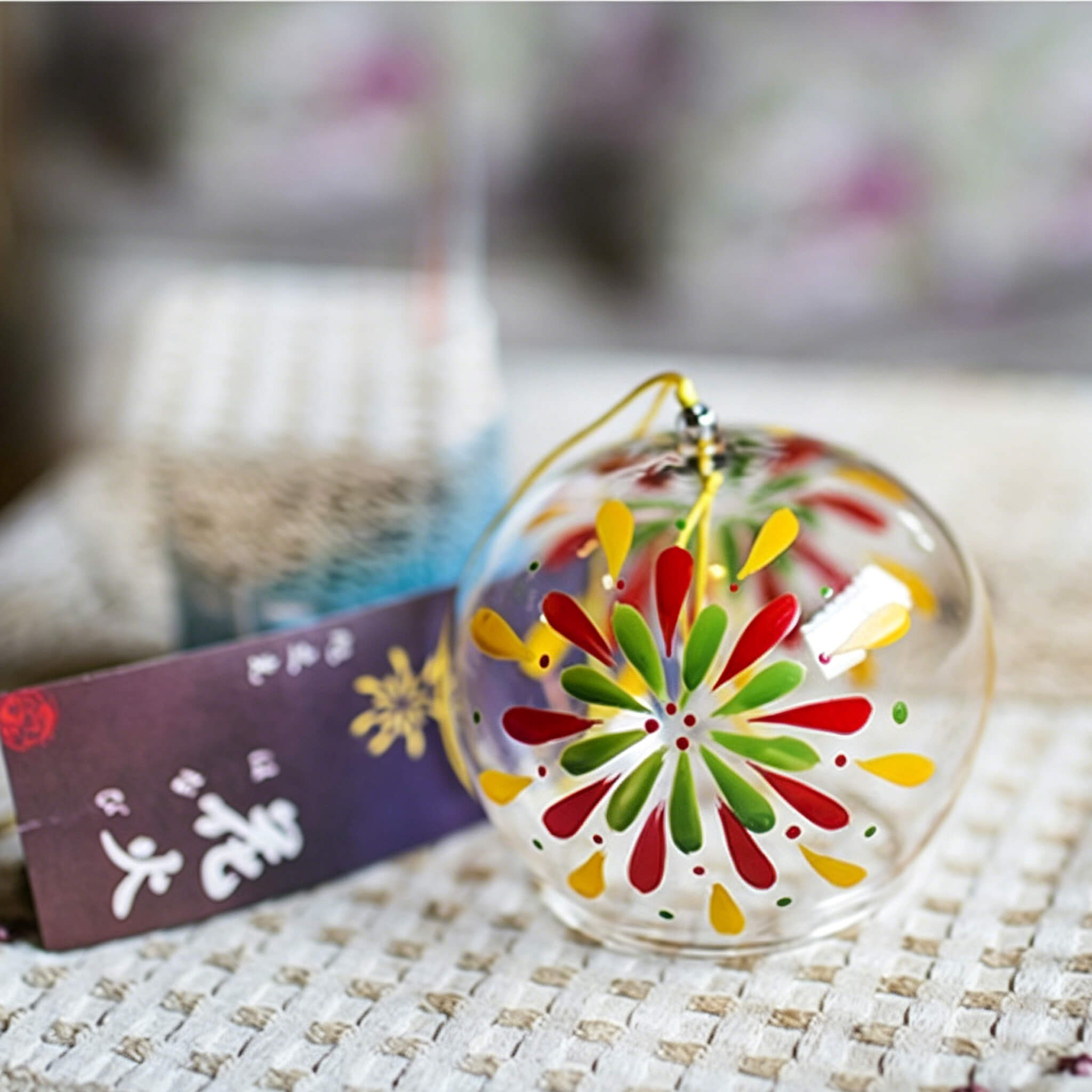 Acever fireworks hanabi glass wind chime X18 resting on table showing clear flat-rim globe with multicolour fireworks burst and  paper strip