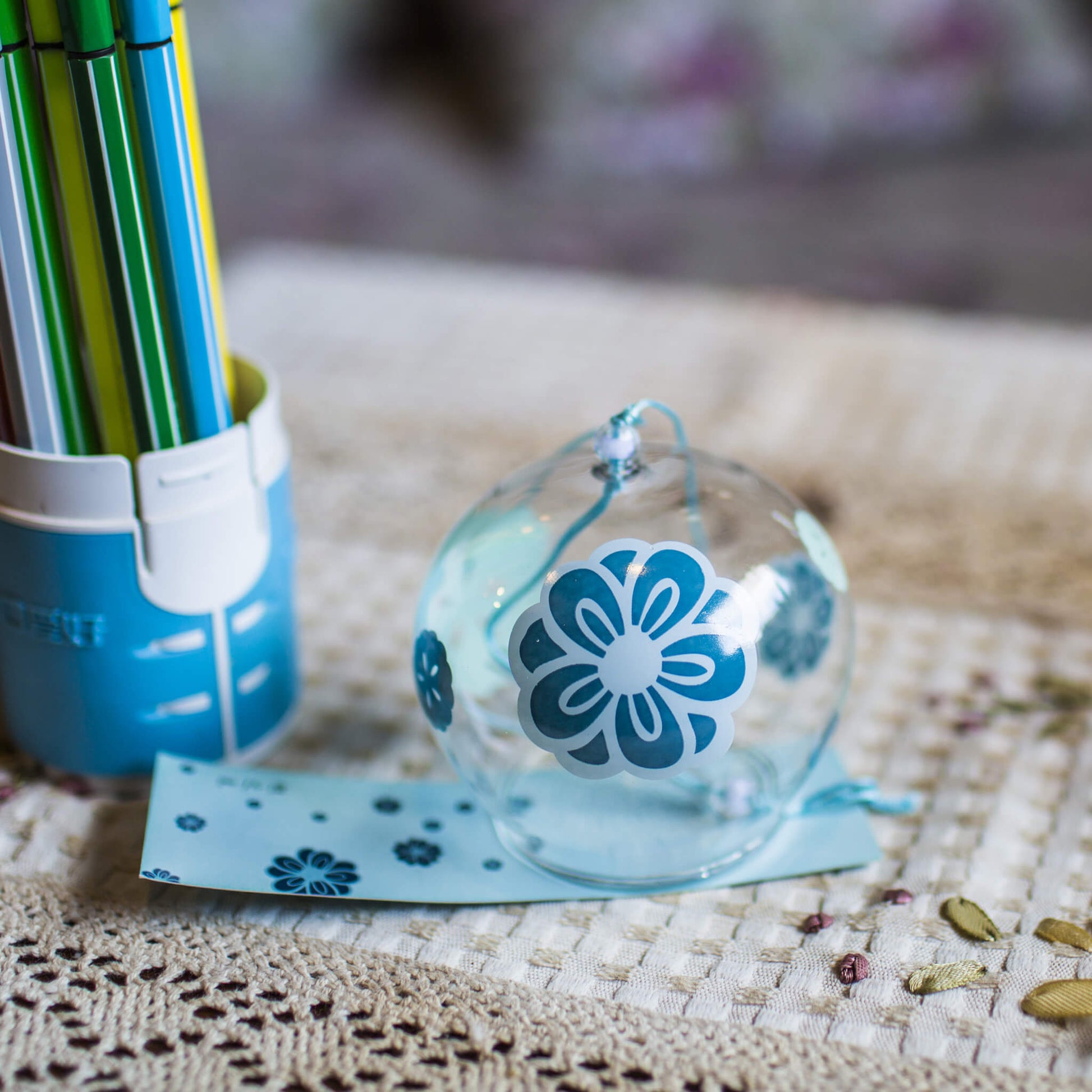 Acever teal plum blossom glass wind chime X19 on table showing clear globe with teal ume design and blue paper strip