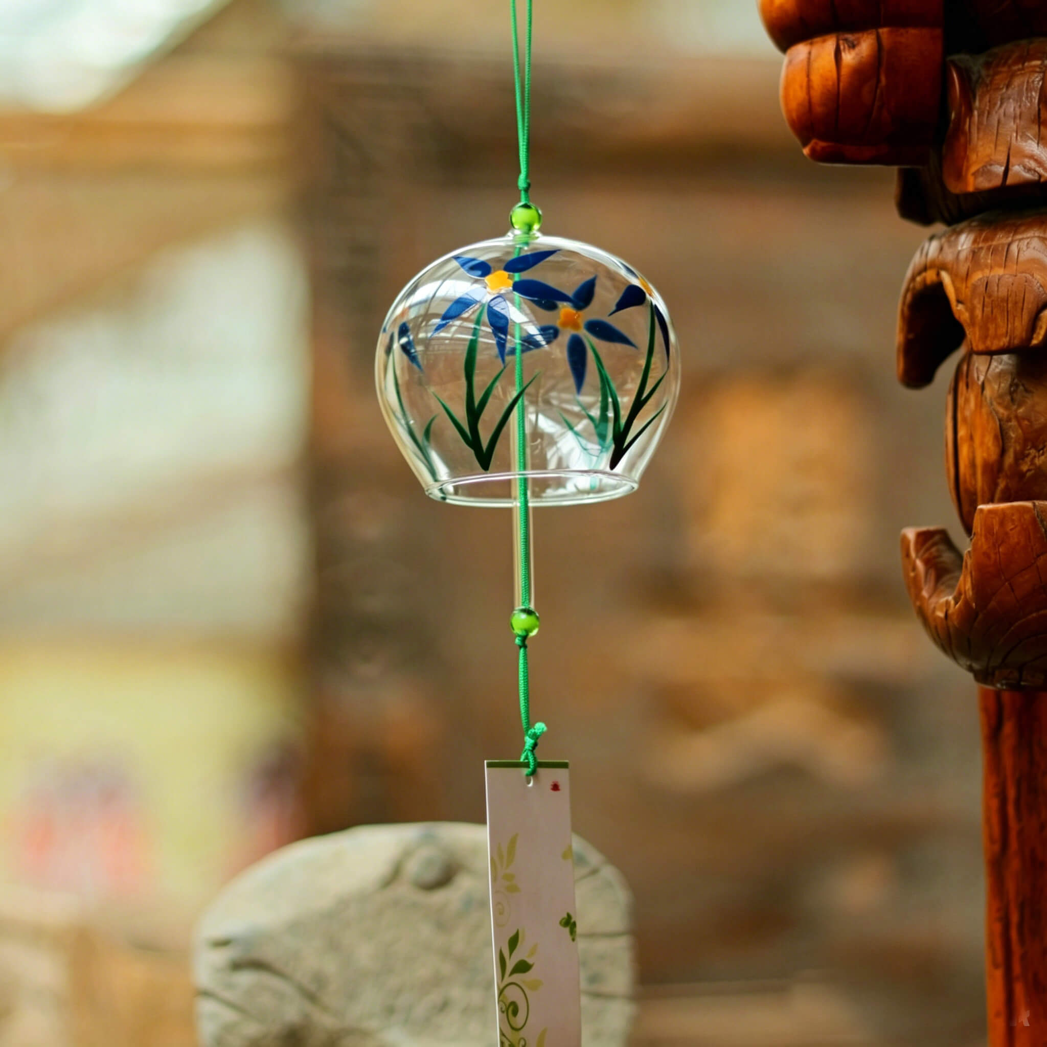 Acever blue daisy glass wind chime X23 hanging on traditional Chinese temple carved wooden pillar and stone ram sculpture showing clear globe with blue daisy blossoms and white paper strip