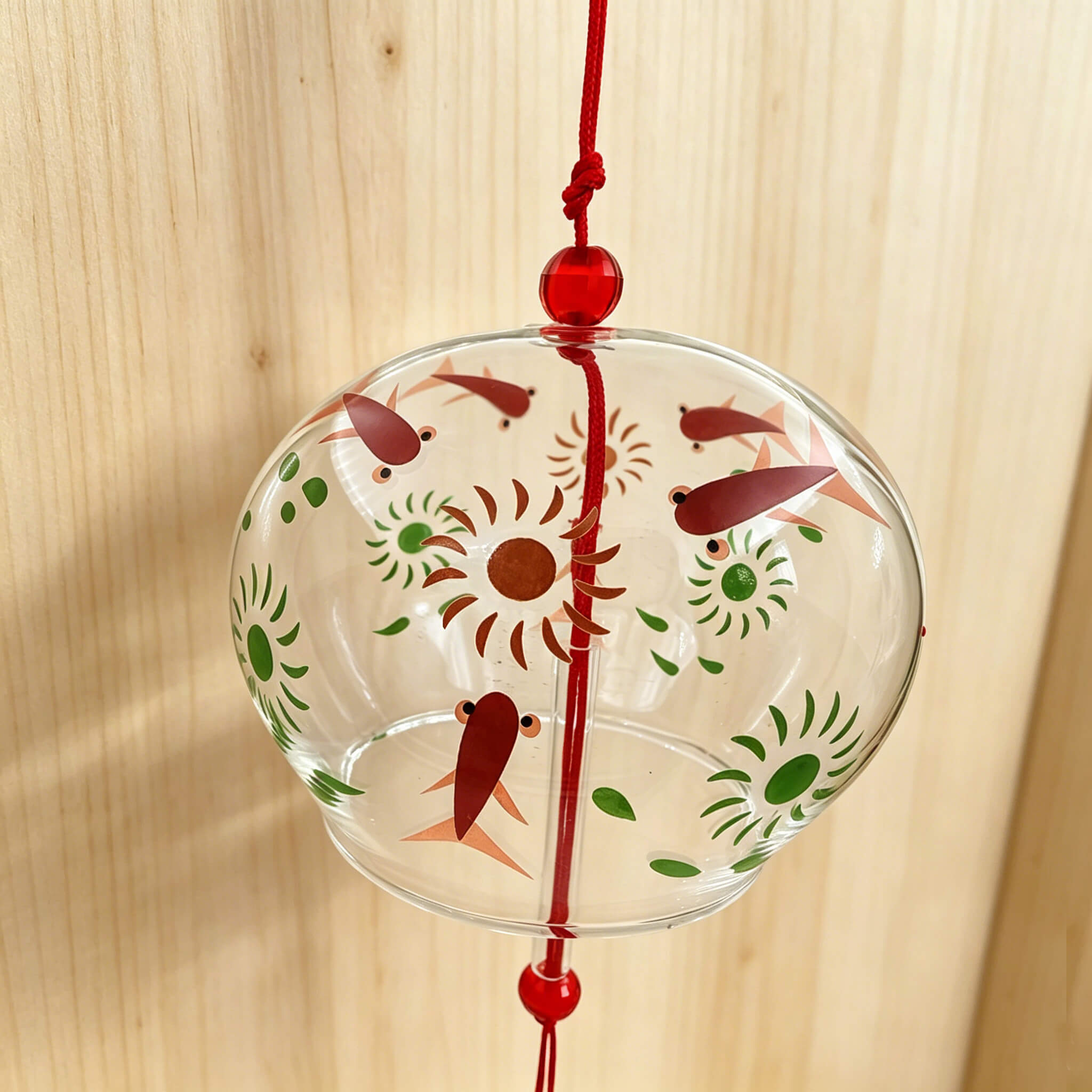 Close-up of Acever red goldfish glass wind chime X27 hanging against wooden background showing clear globe with red kingyo fish and green flower blooms