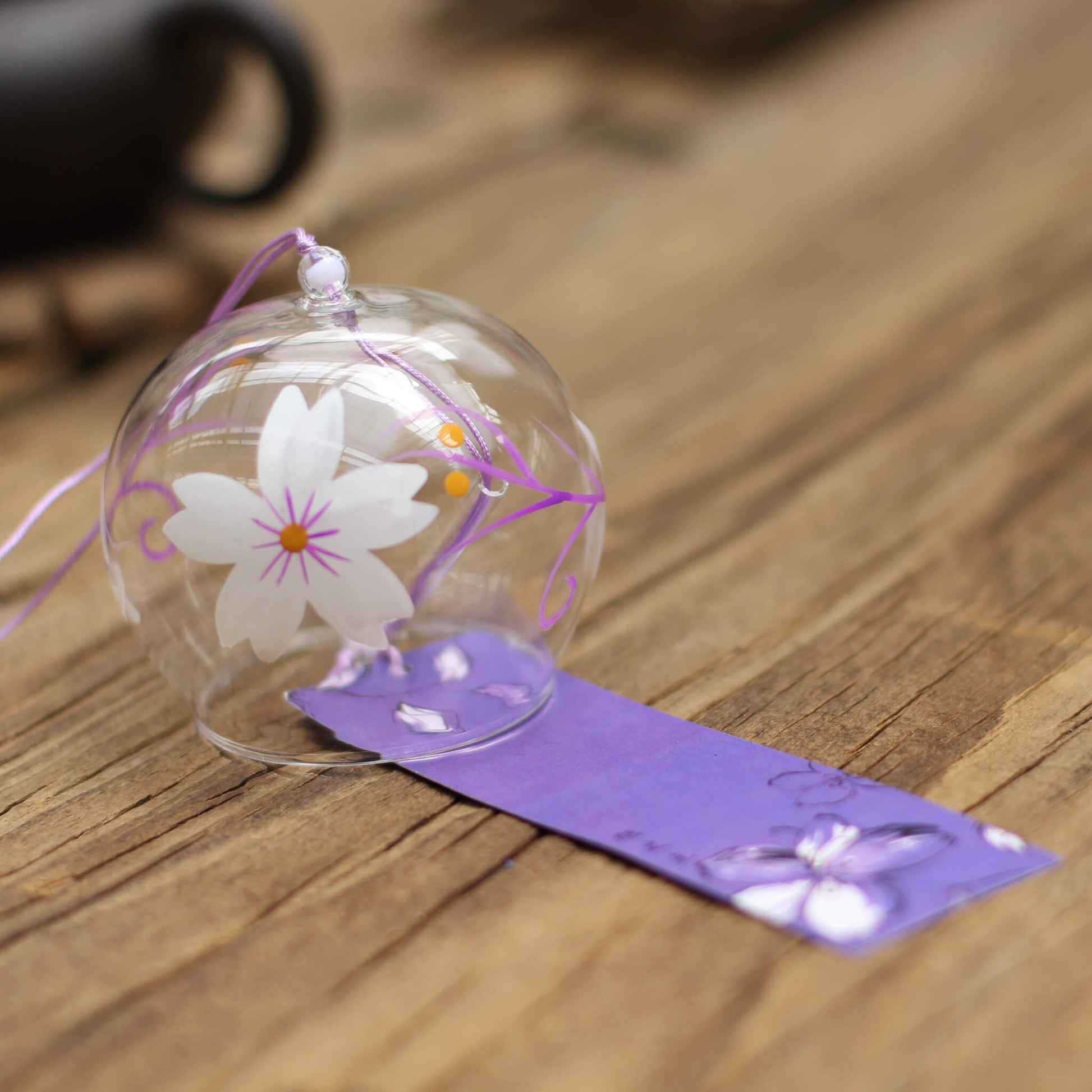 Side view of Acever white magnolia pink vine glass wind chime X28 showing clear globe profile with white magnolia blossoms, magenta vine scrolls, purple cord, and violet iris paper strip