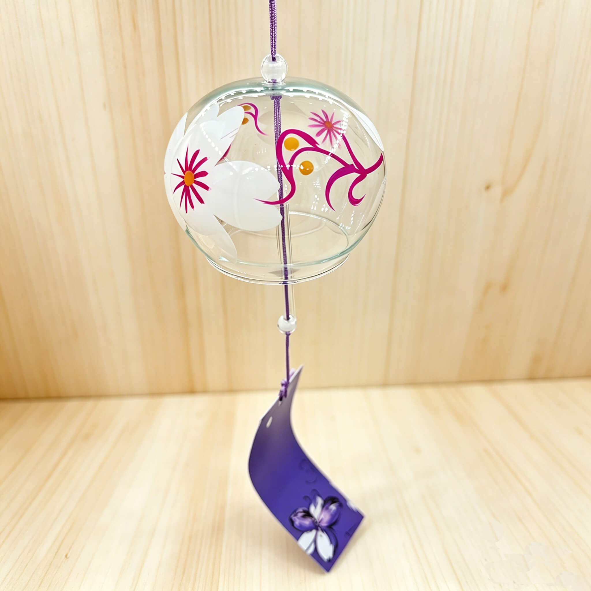 Acever white magnolia pink vine glass wind chime X28 hanging against wooden panel background showing clear globe with white magnolia blossoms, magenta vine scrolls, and violet iris paper strip