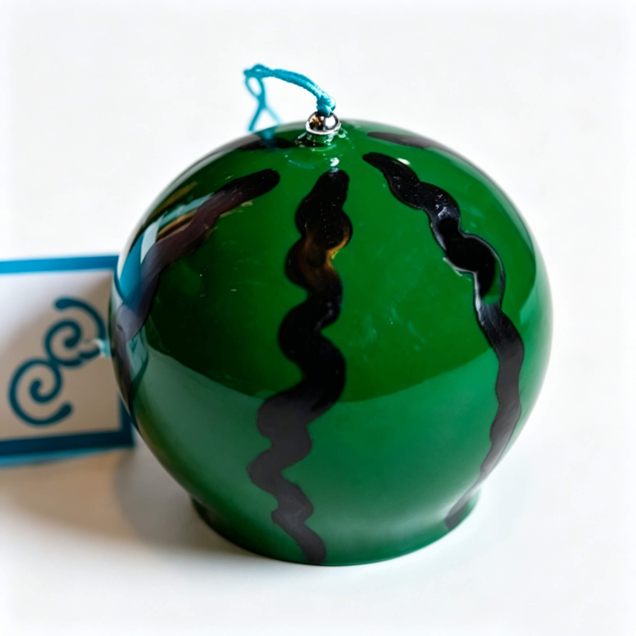 Close-up of Acever watermelon glass wind chime X31 on white background showing deep forest green globe with bold black wavy zigzag stripes and teal cord with silver bead