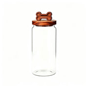 Clear smooth glass jar with round wooden lid featuring carved bone-shaped handle.