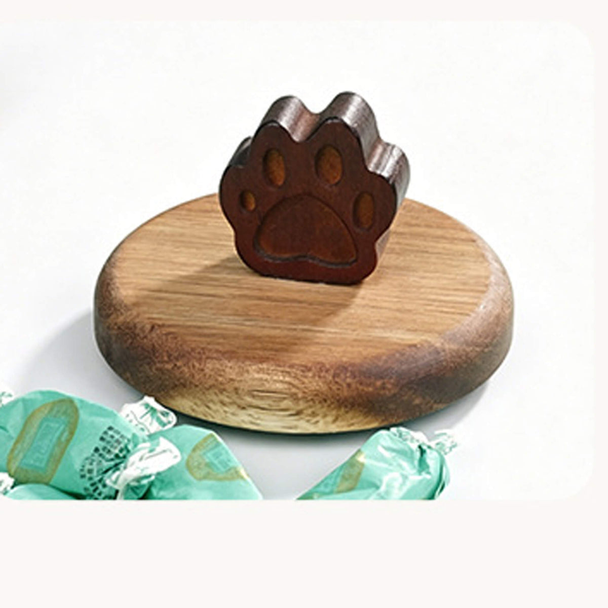 Carved wooden cat paw handle on round wooden lid next to wrapped candies.