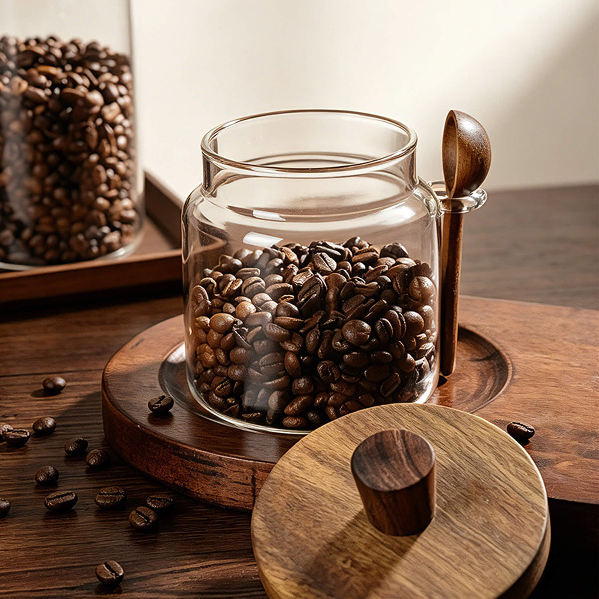 Open smooth glass jar filled with coffee beans and solid wood knob lid placed on wooden tray.