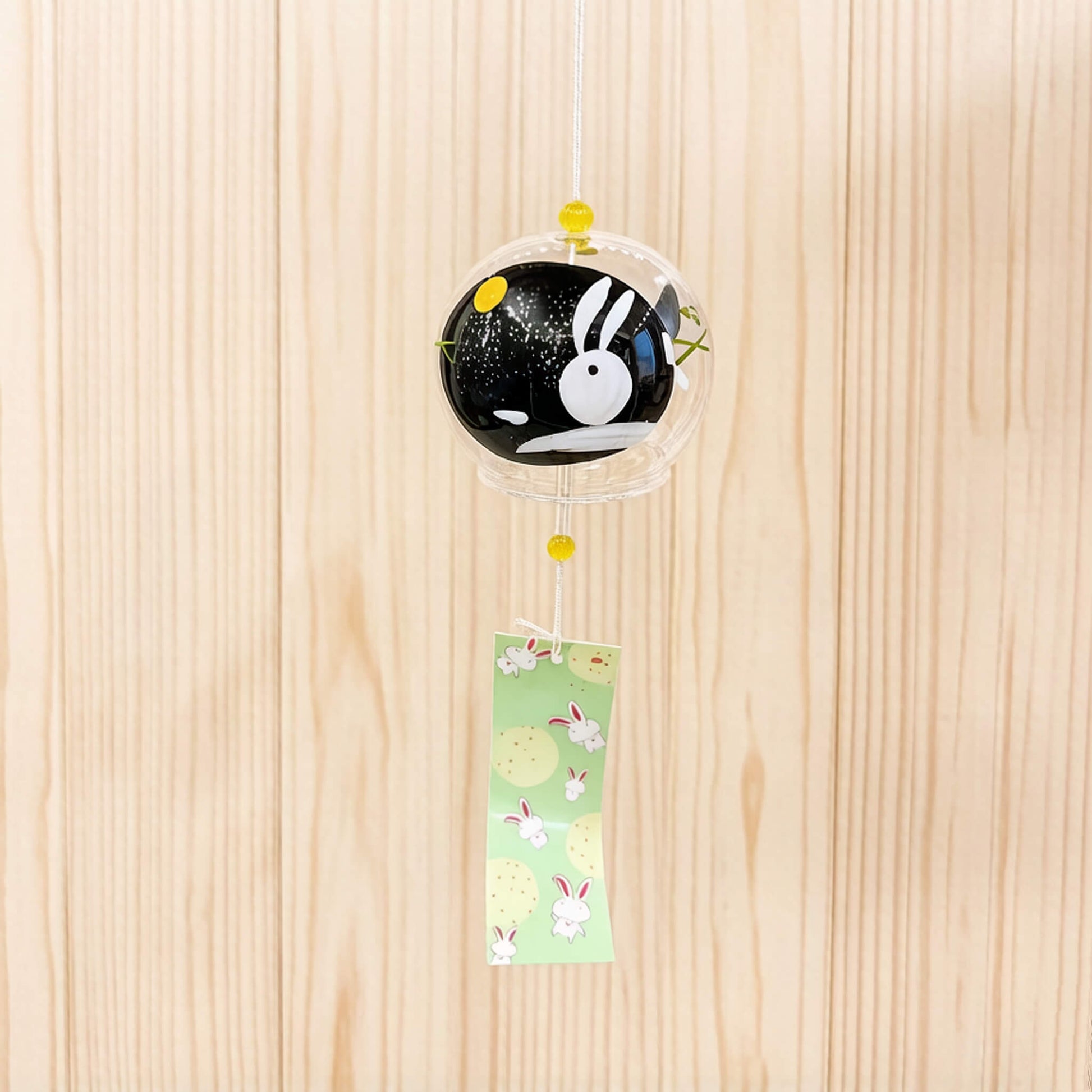 Acever Moon Rabbit glass wind chime X36 hanging with wooden plank surface background showing clear globe with black night sky interior, white rabbit silhouette, and gold moon