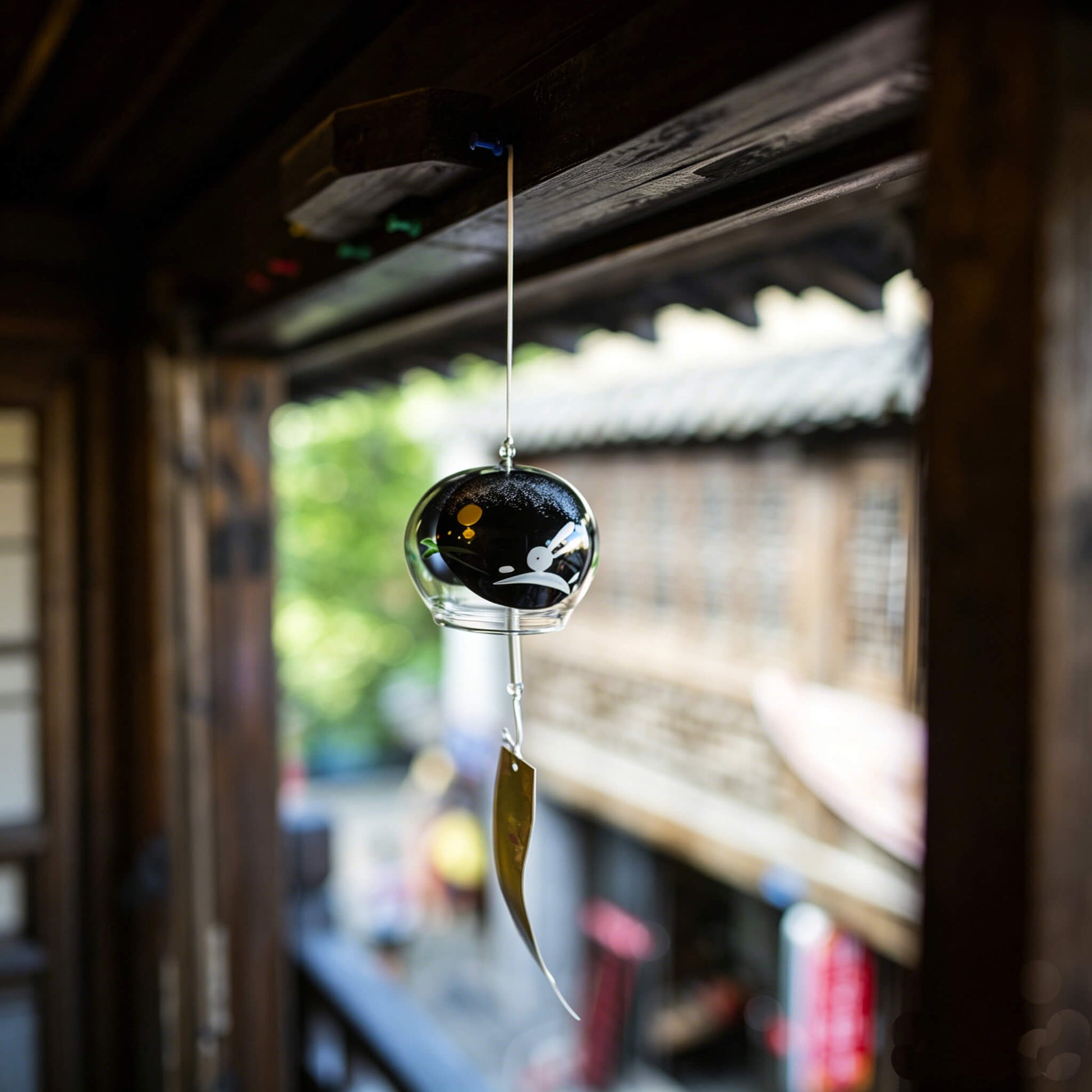 Acever Moon Rabbit glass wind chime X36 hanging from traditional Japanese wooden eave corridor in old street showing clear globe with black night sky, white moon rabbit, and gold full moon