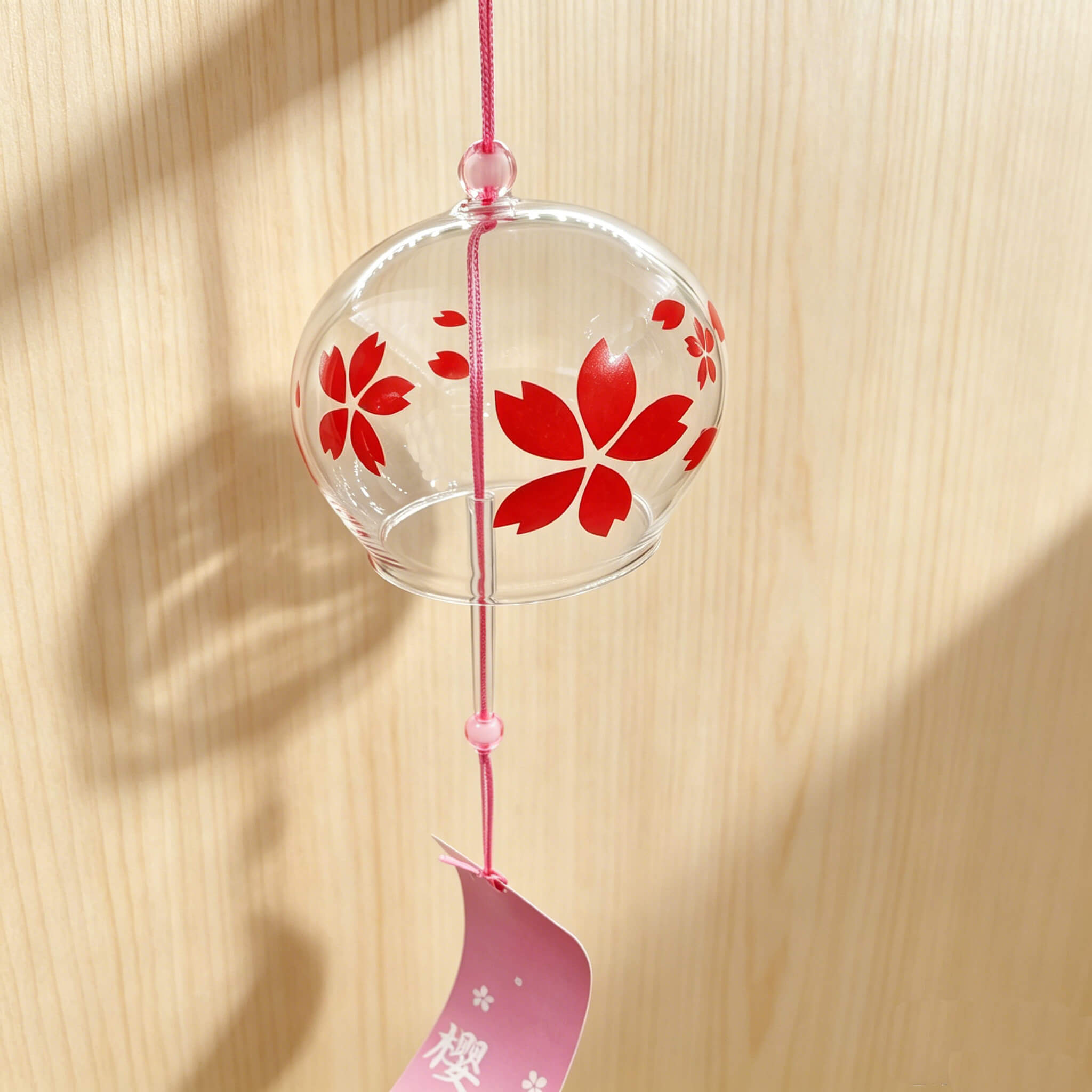 Acever red sakura glass wind chime X37 with wooden plank surface background showing clear globe with vivid red cherry blossoms and pink sakura paper strip