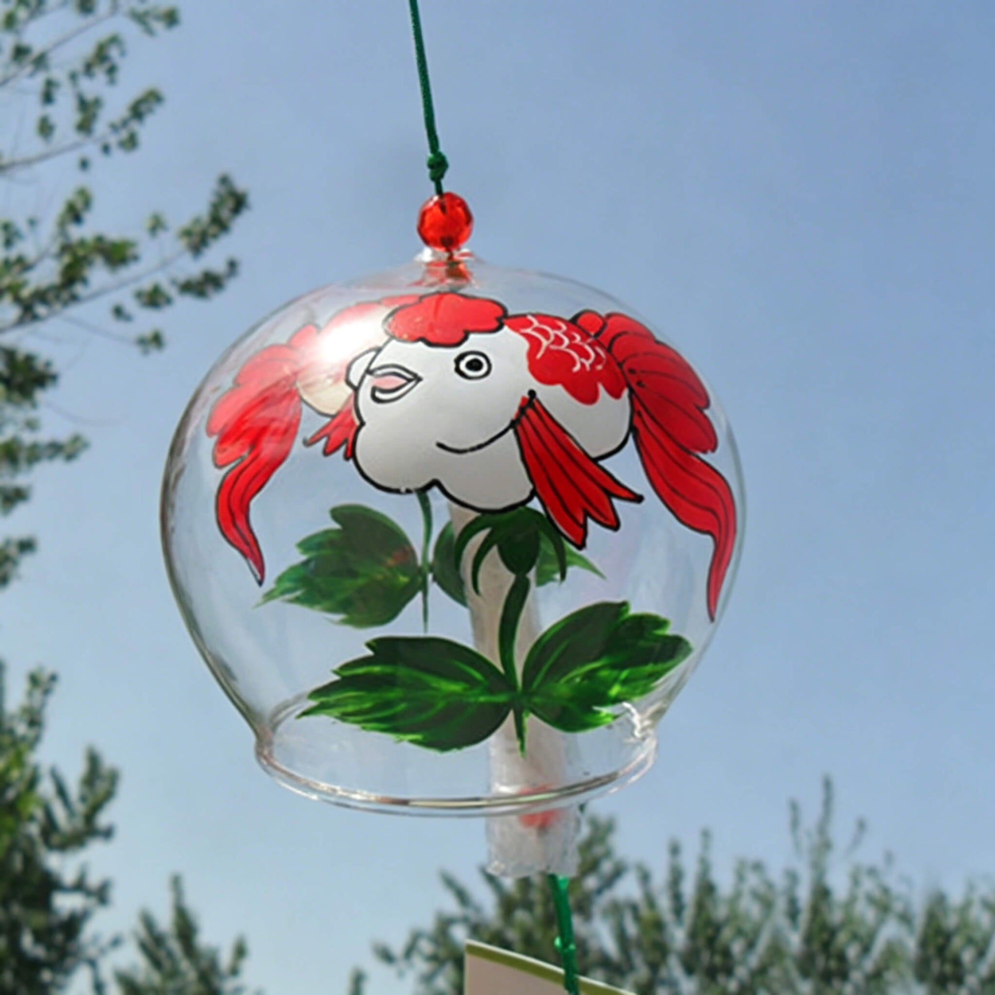 Back view of Acever goldfish glass wind chime X39 on wooden plank surface showing clear ribbed globe with white goldfish with red head markings and red fins and green lotus leaves
