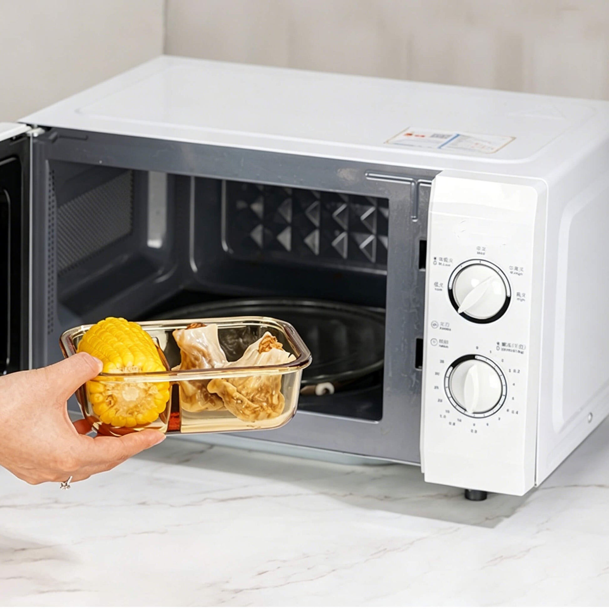 Hand placing Acever BX04 borosilicate glass food container into microwave oven showing microwave-safe glass body