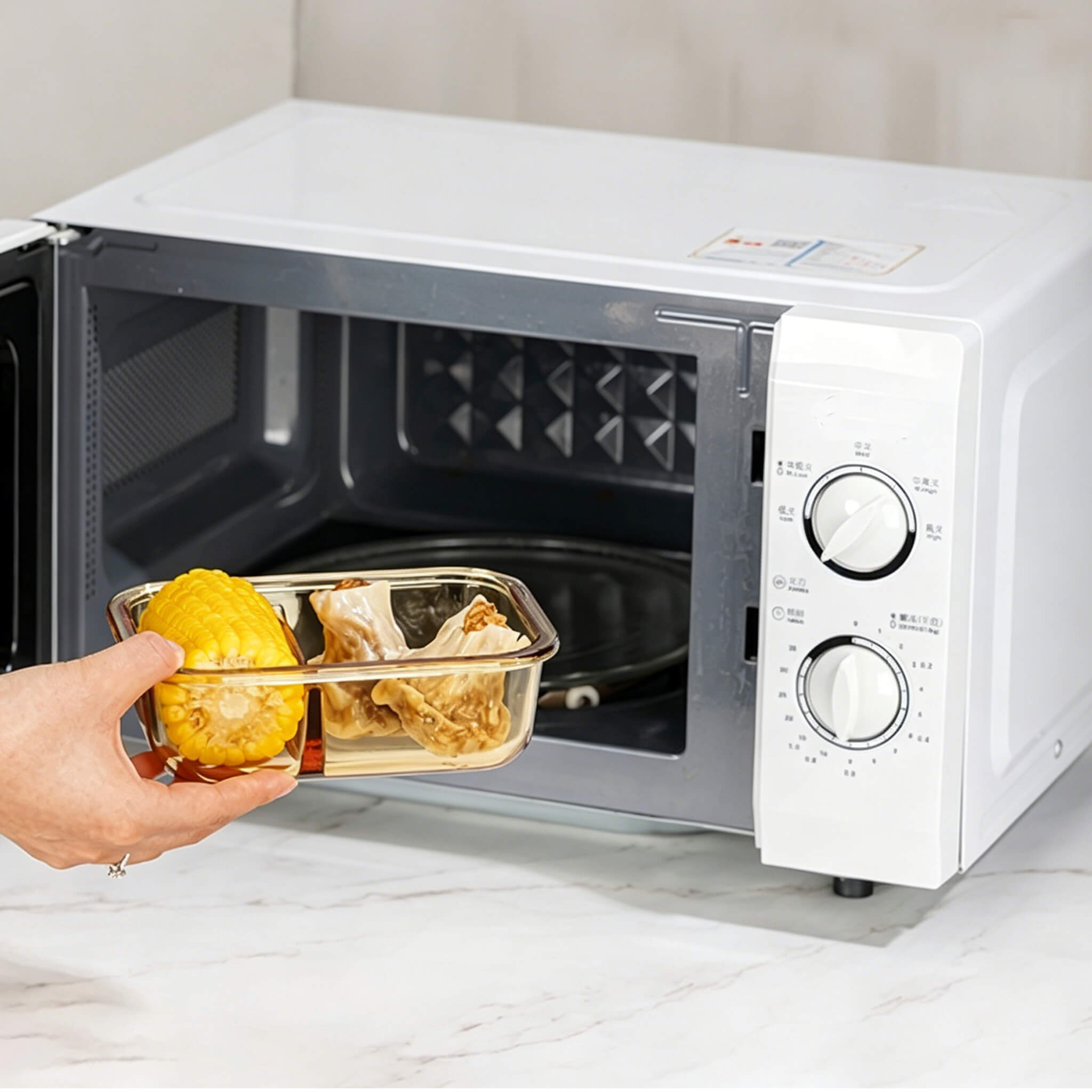 Hand placing Acever BX04 borosilicate glass food container into microwave oven showing microwave-safe glass body
