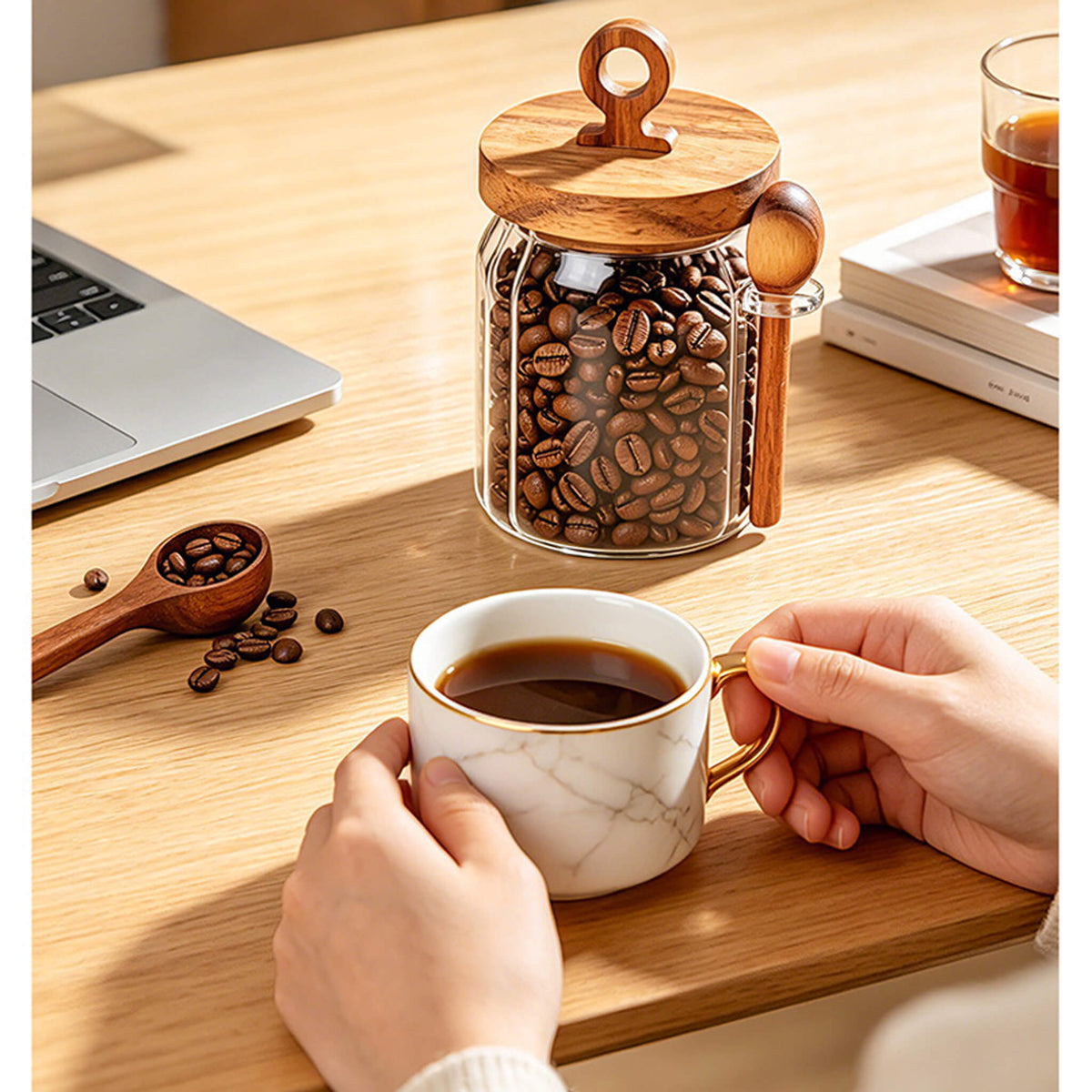 Hand holding ribbed glass jar filled with tea leaves next to walnuts on table.