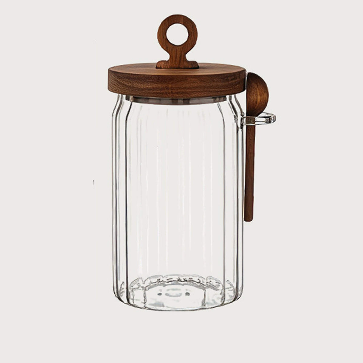 Clear ribbed glass jar with wooden lid, ring handle, and wooden spoon in glass side holder.