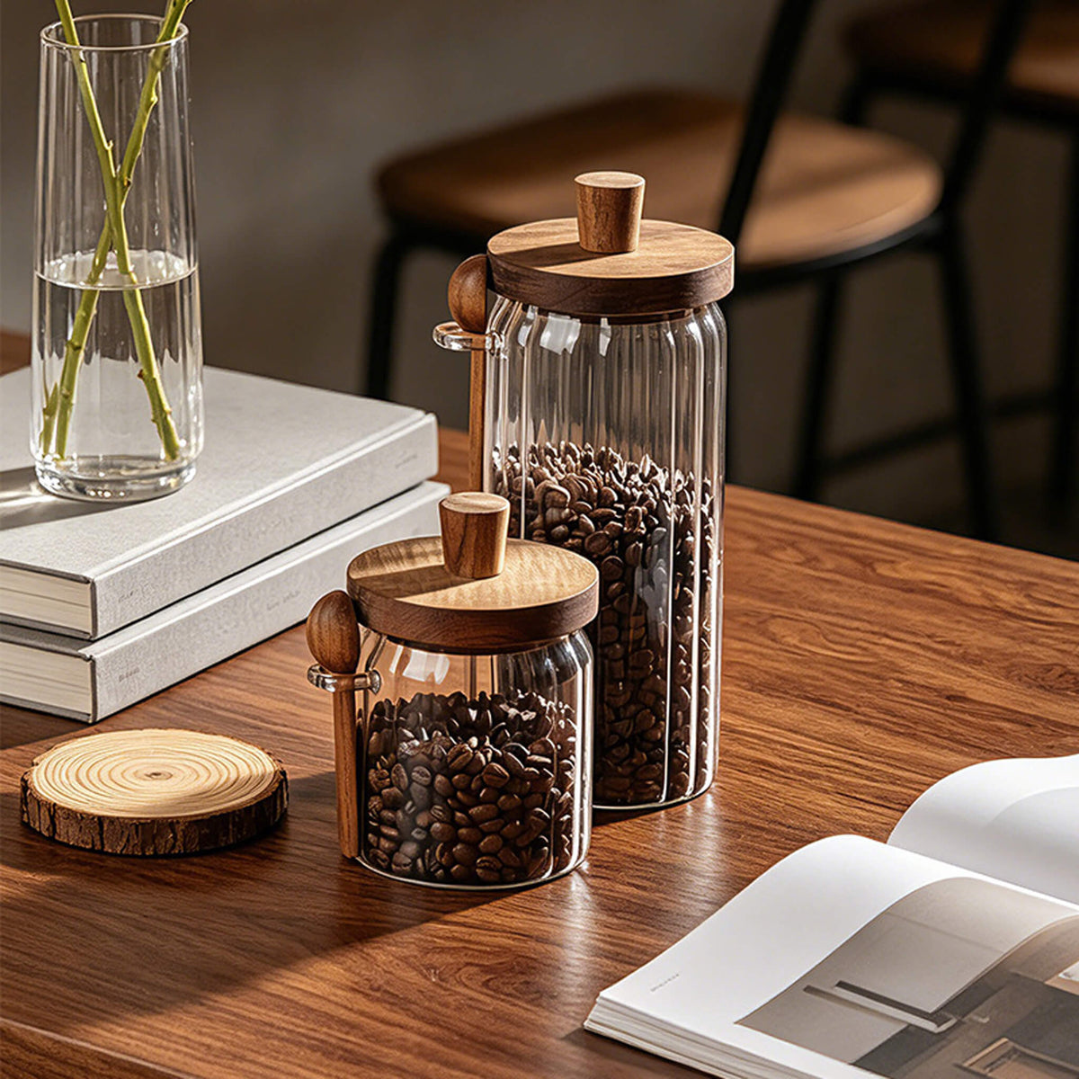 Two ribbed glass jars with solid wood knob lids filled with coffee beans on wooden desk.
